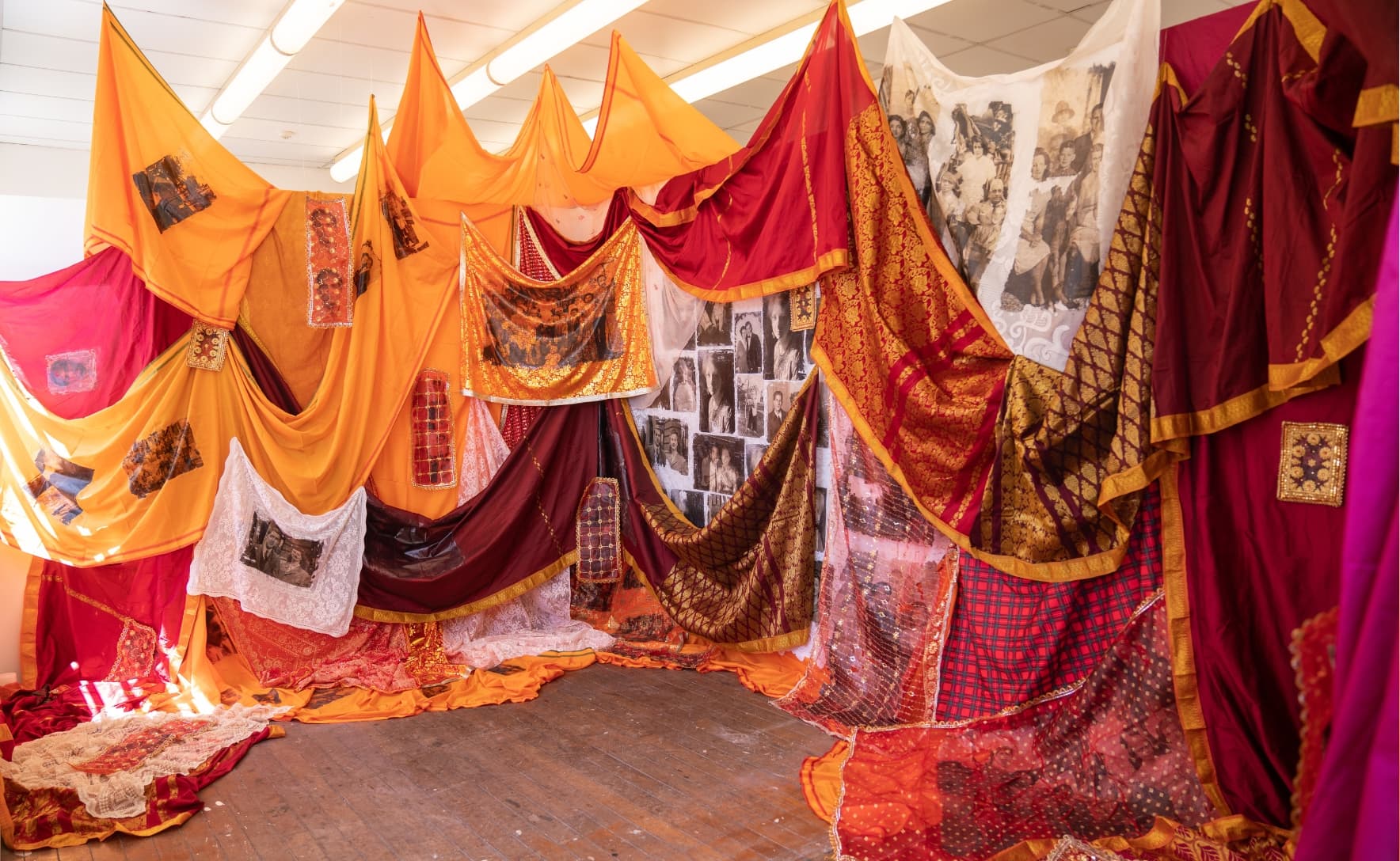 red, orange and white fabric is draped in a small room space