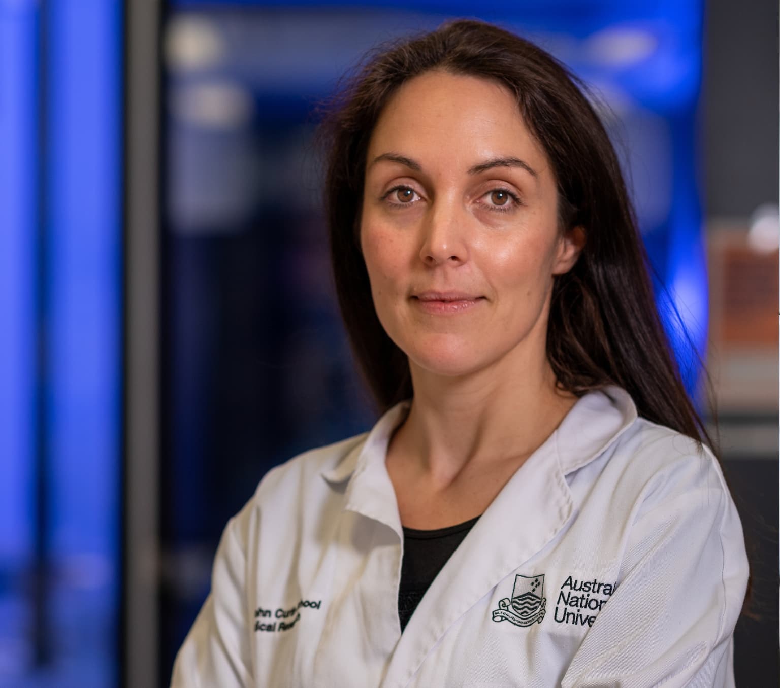 Marian is pictured in a laboratory smiling at the camera. She is wearing a white lab coat