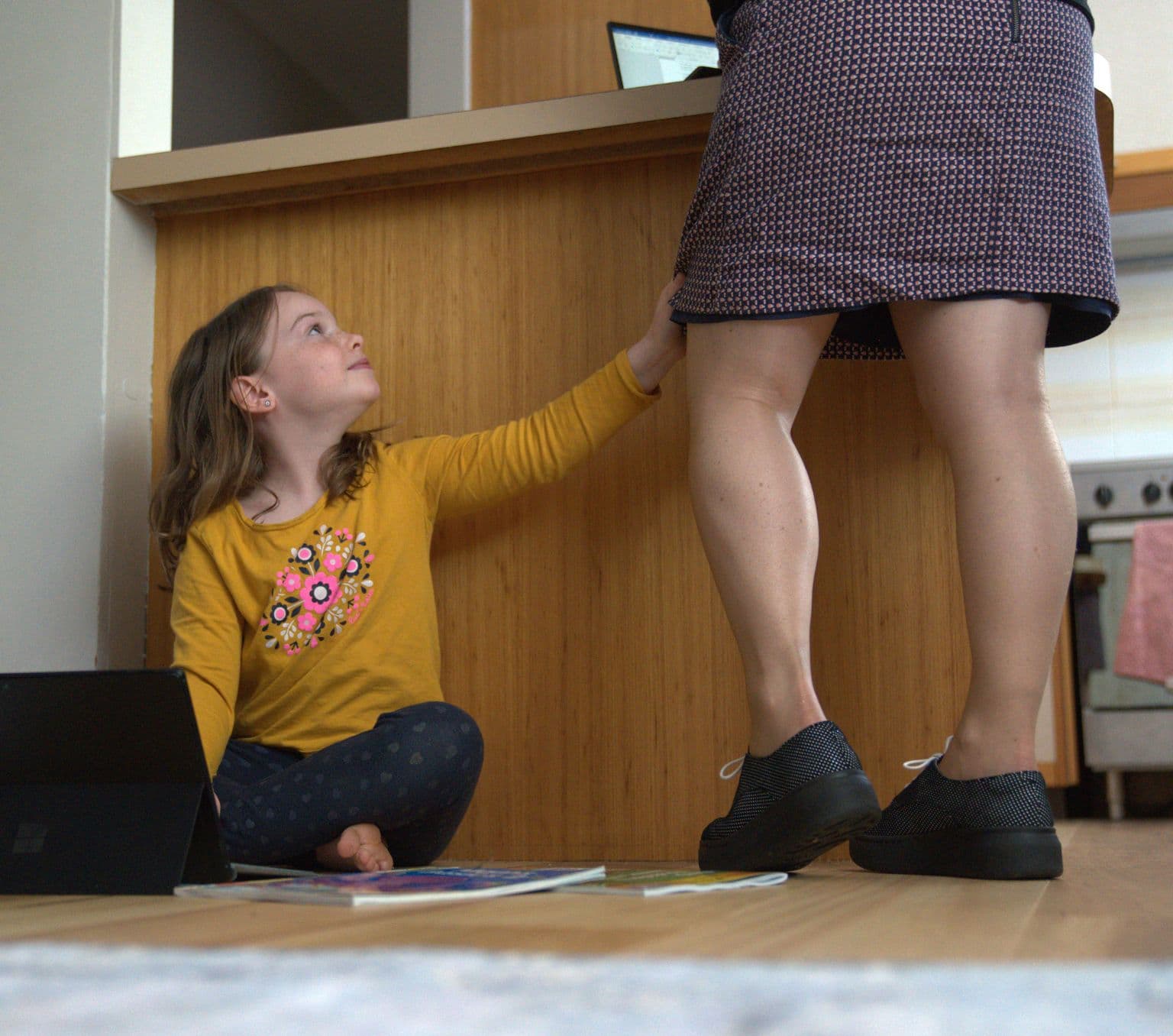 Child completing school work and getting the attention of near by mother.