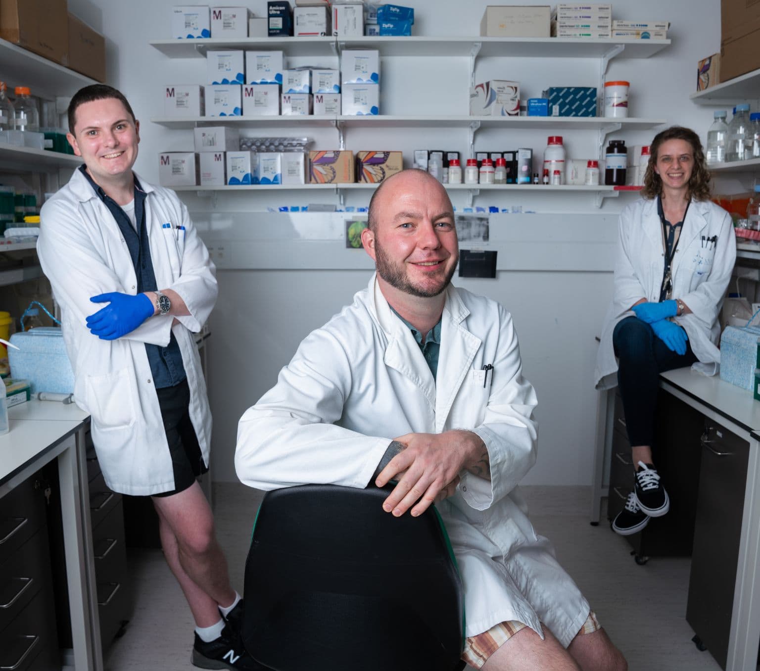 Three people, Dr. Benjamin Schwessinger, Emma Crean and Dr. Ashley Jones, in their lab. They’re all wearing white lab coats.