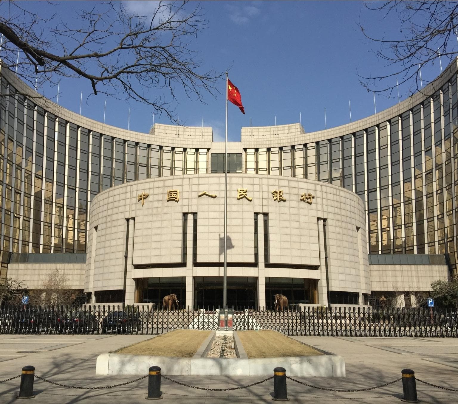 White tiled round building with a red Chinese flag flying at the centre.