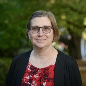 Professor Ute Roessner smiles at the camera. She is outside and green trees can be seen in the distance.