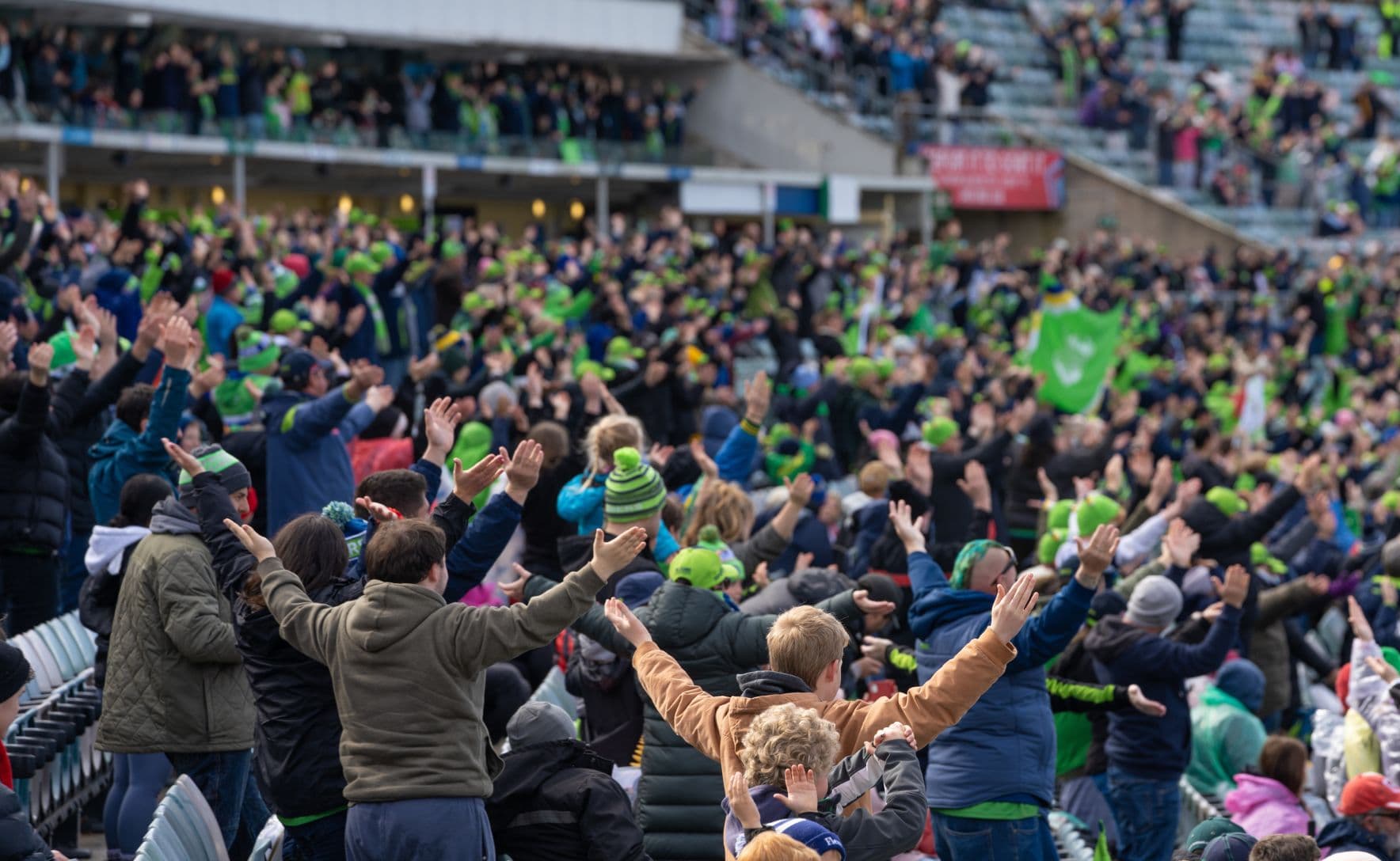 Crowd of supporters at NRL game clap in unison