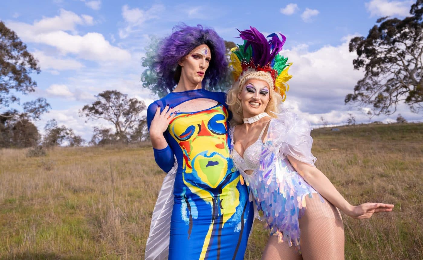 A combination of drag queens, ballet dancers and Brazilian funk dancers wearing colourful costumers filled to the brim with sequins. They are all dancing in a field in regional Victoria.