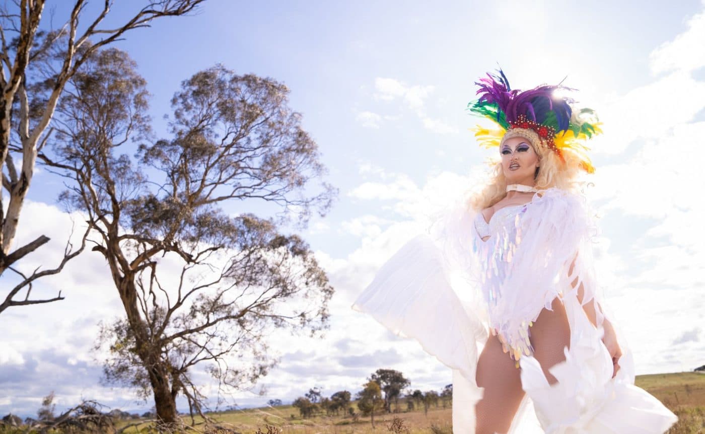 A combination of drag queens, ballet dancers and Brazilian funk dancers wearing colourful costumers filled to the brim with sequins. They are all dancing in a field in regional Victoria.