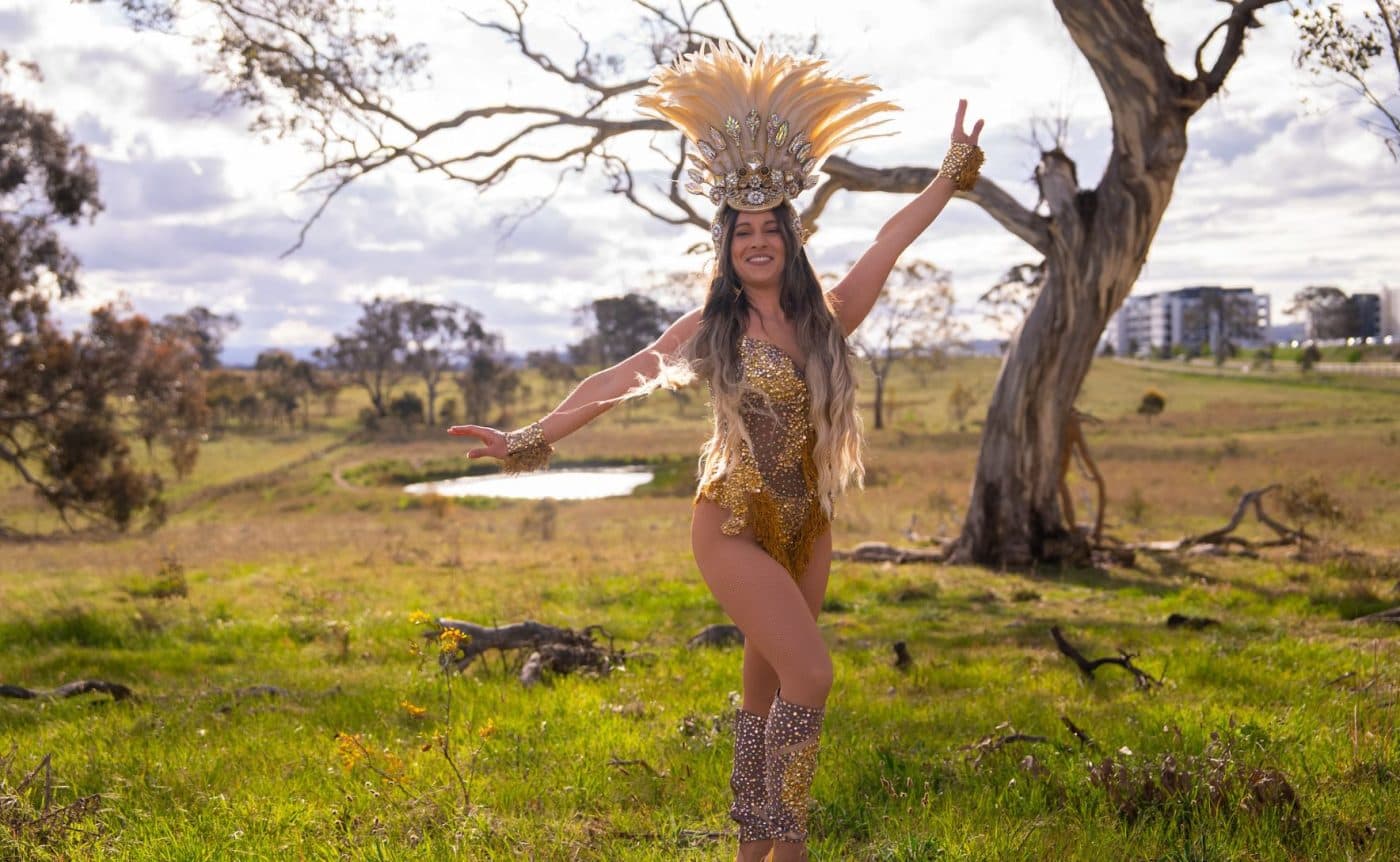 A combination of drag queens, ballet dancers and Brazilian funk dancers wearing colourful costumers filled to the brim with sequins. They are all dancing in a field in regional Victoria.