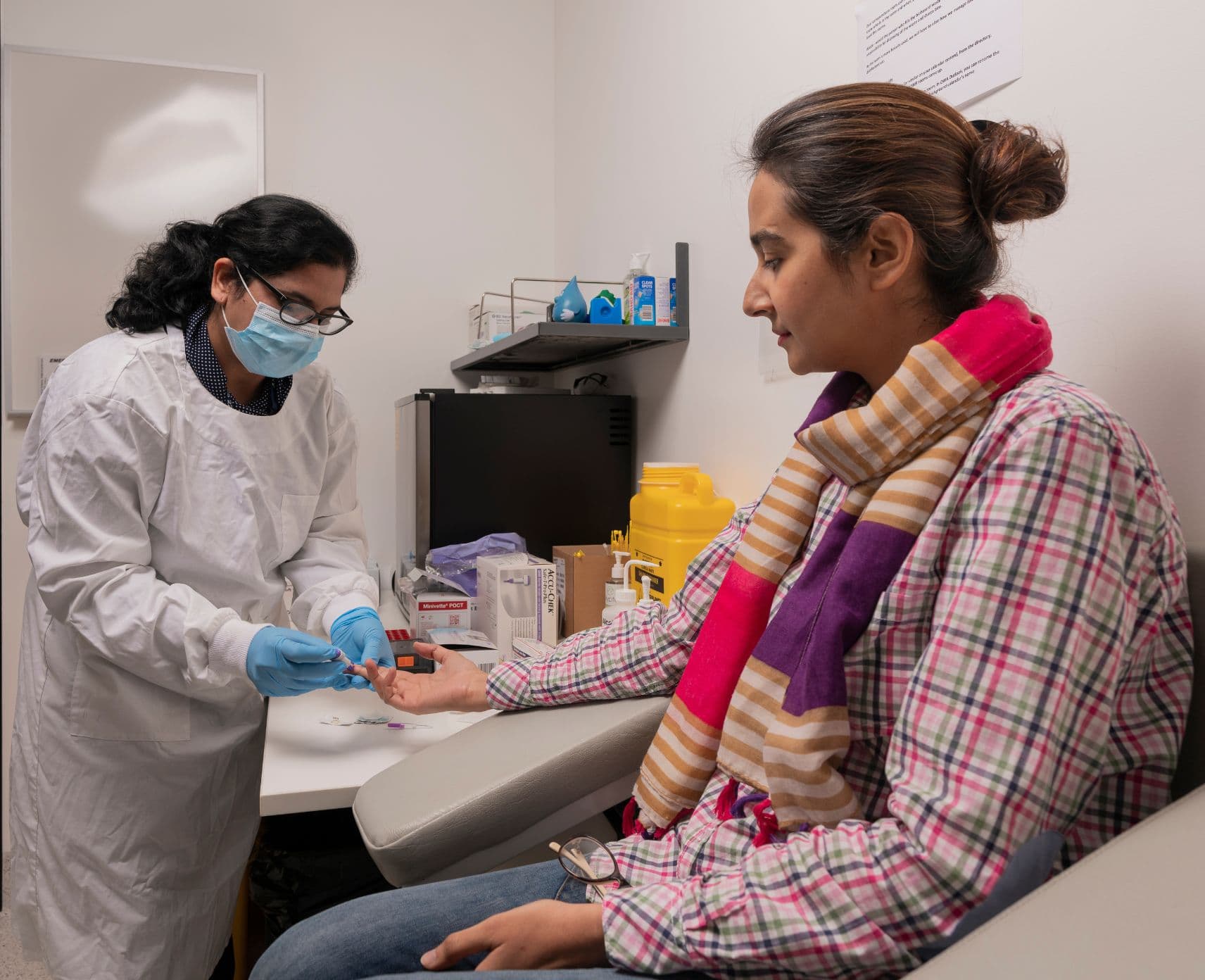 A patient has a blood sample taken by a woman in a white lab coat.