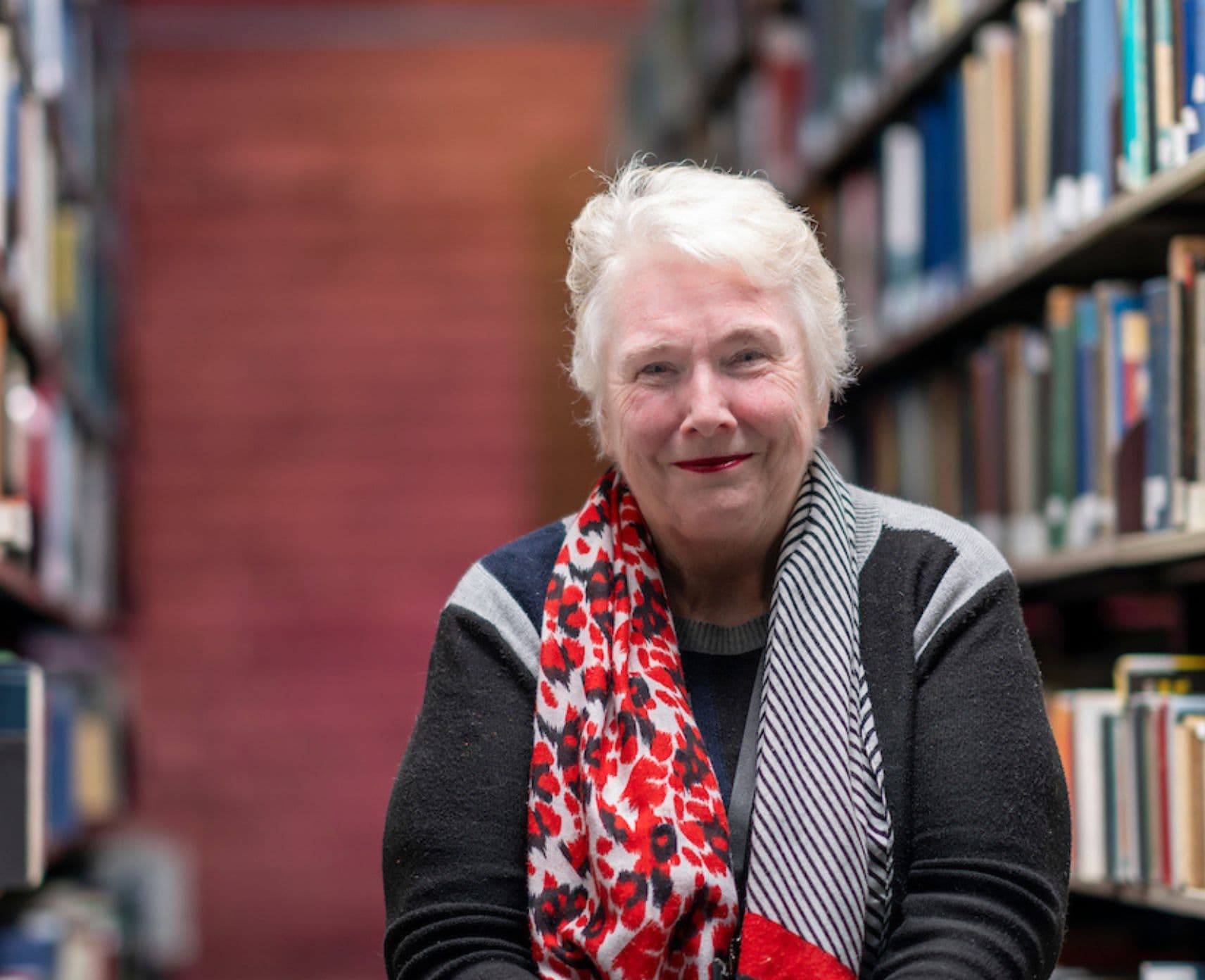 Roxanne Missingham stands in an aisle between two rows of books.