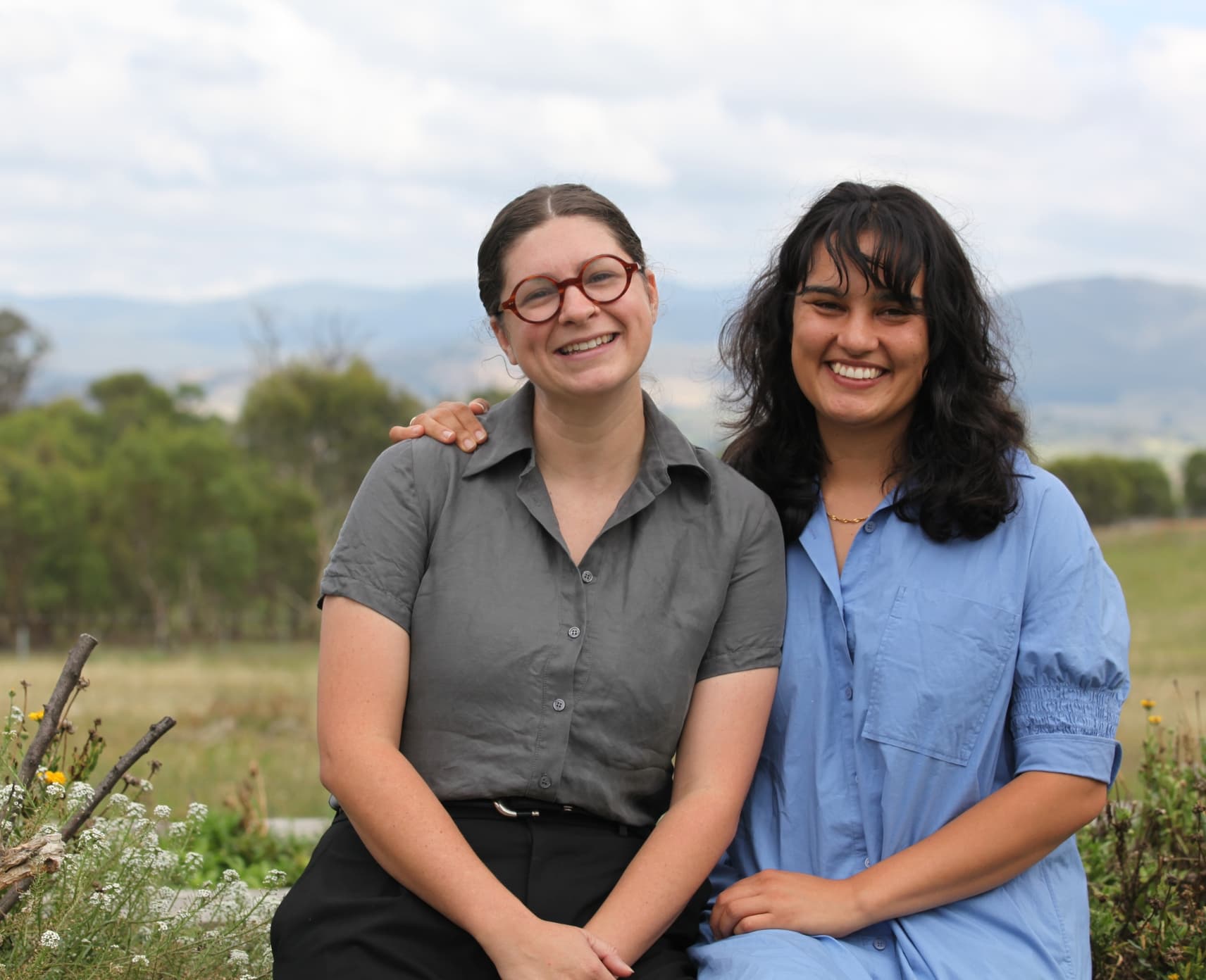 Hannah Costello and Vanessa Brettell in field with distant mountains