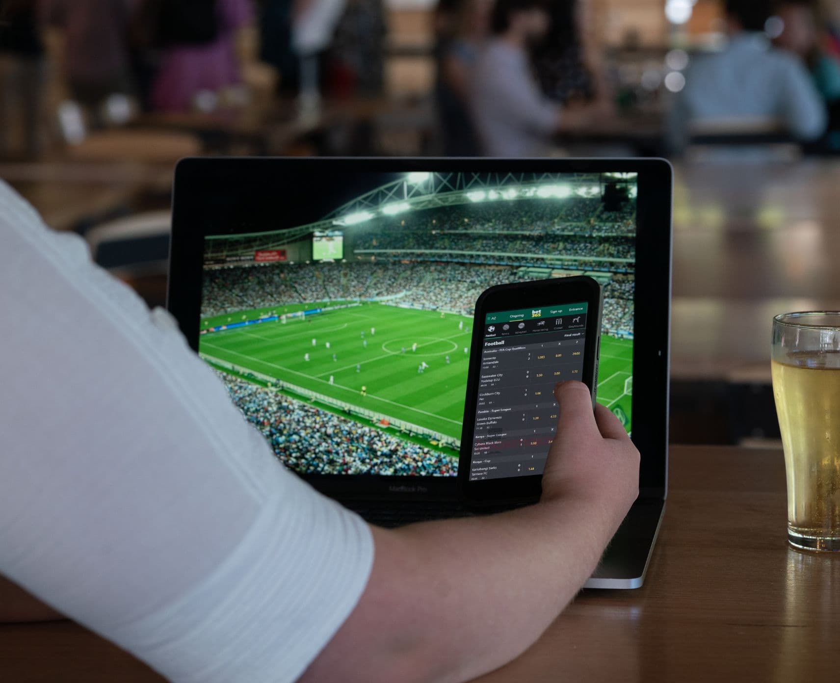 Close up of a young person watching sport on their laptop and using a betting app