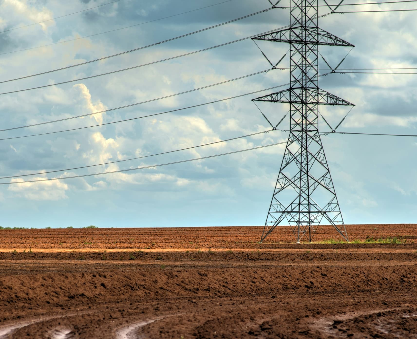 Powerlines in red dirt in a rural landscape.
