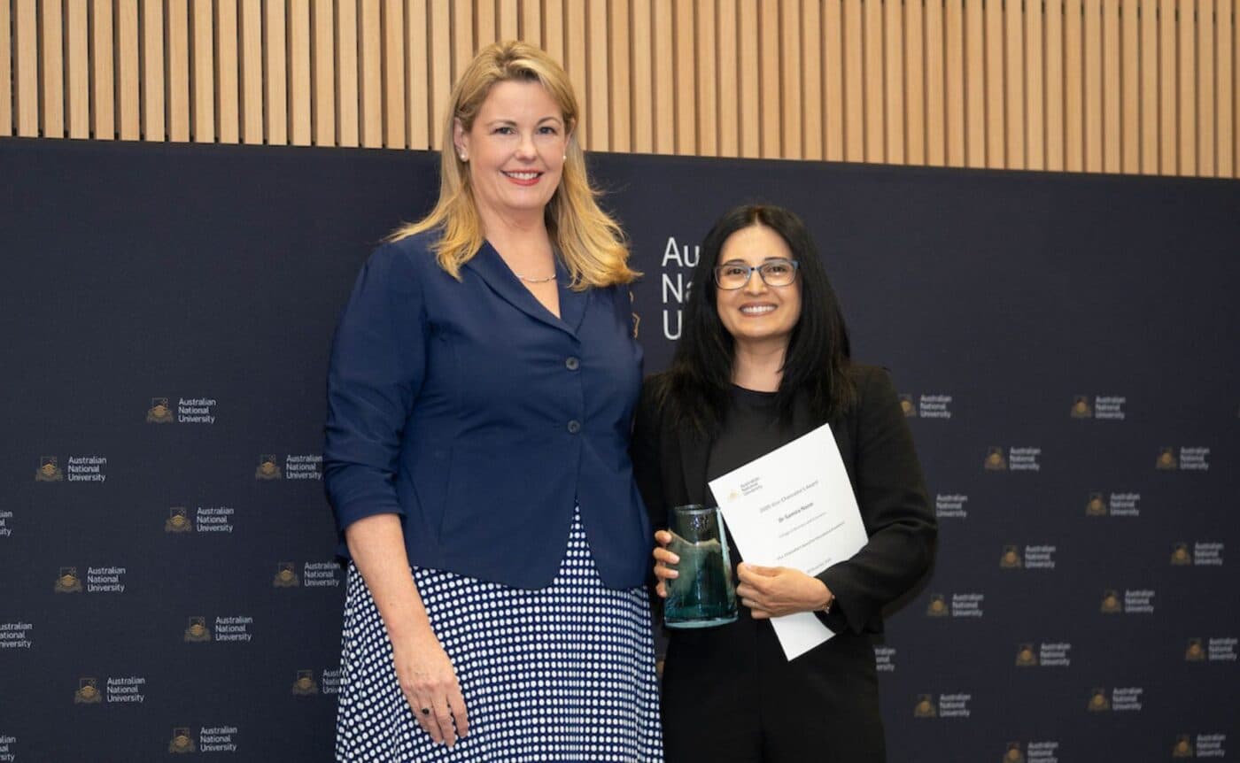 Two people pose with an award