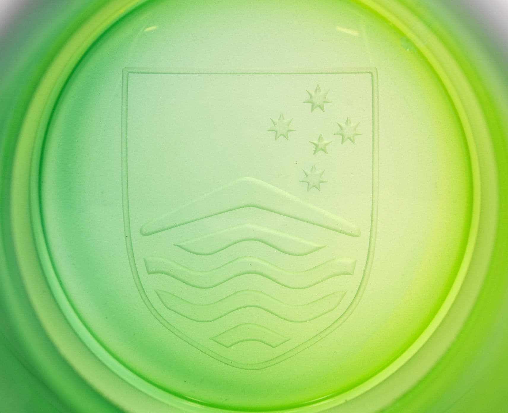Close up of a green glass sculpture showing the ANU logo