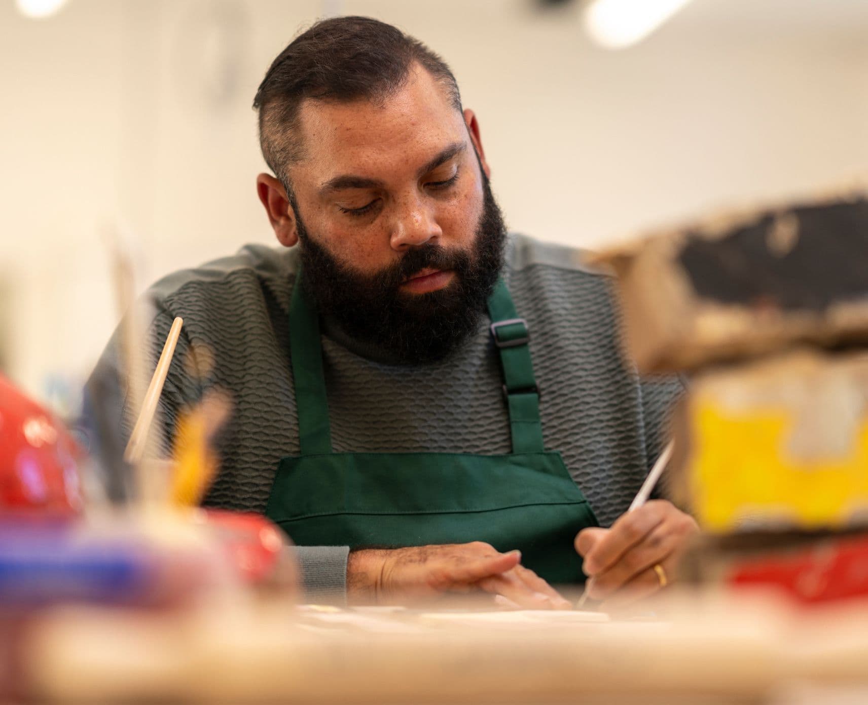 An artist in a studio painting ceramics