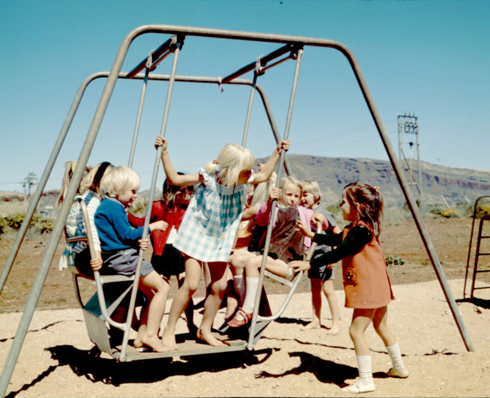 Archival photo of small children on a swing outdoors