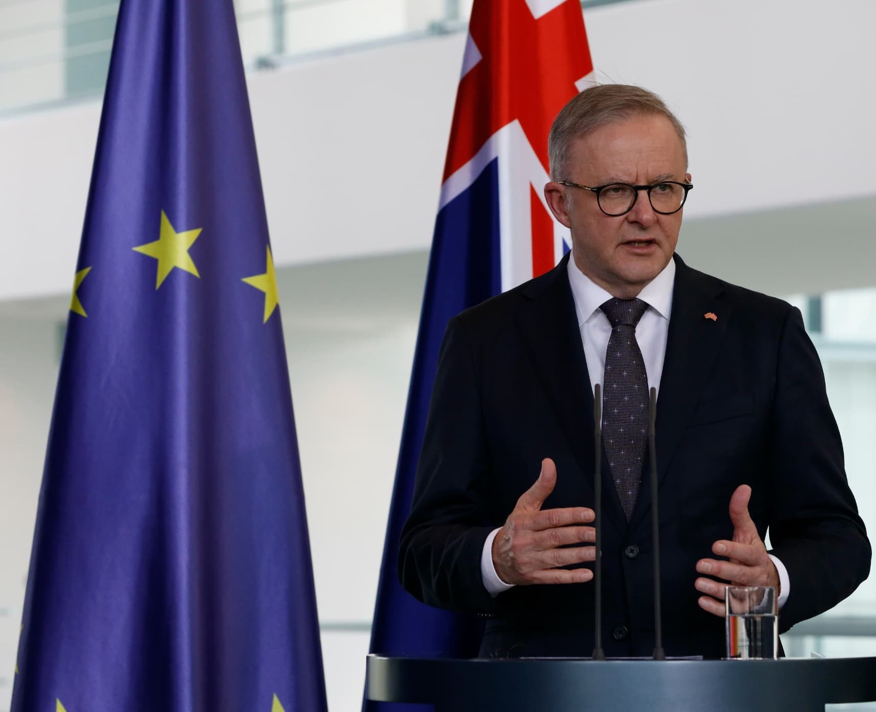Australian Prime Minister Anthony Albanese standing in front of an Australian flag and a European flag