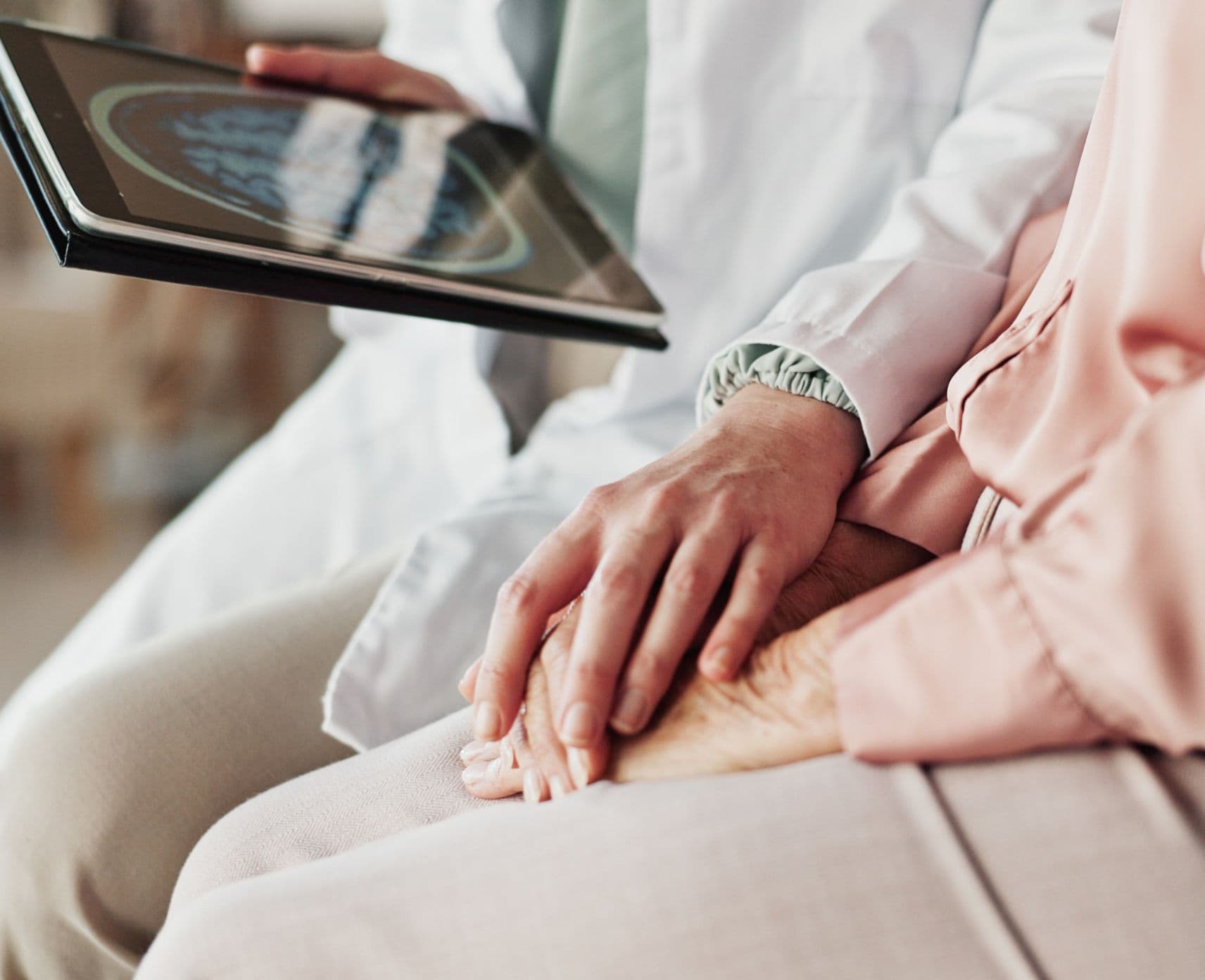An elderly woman looks at a brain scan image on a digital device.