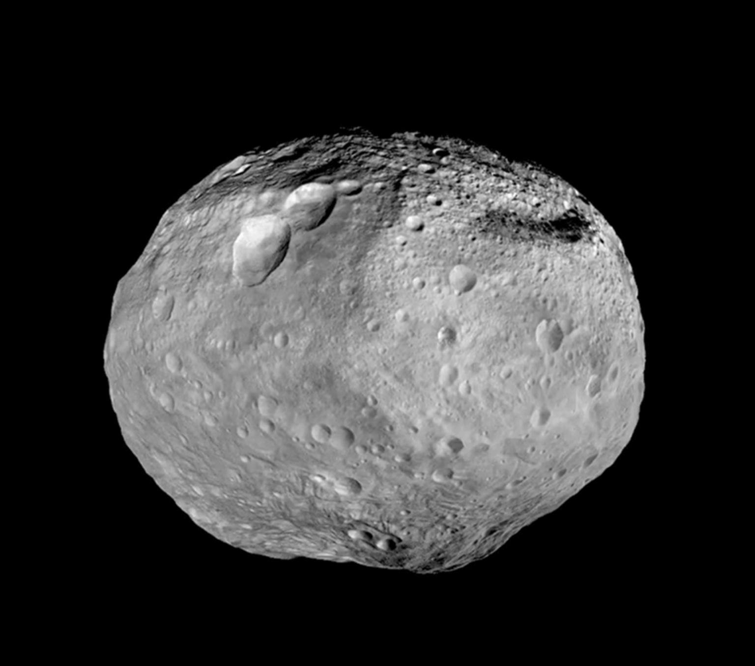 black and white image of an asteroid. It is a grey round rock with dents.