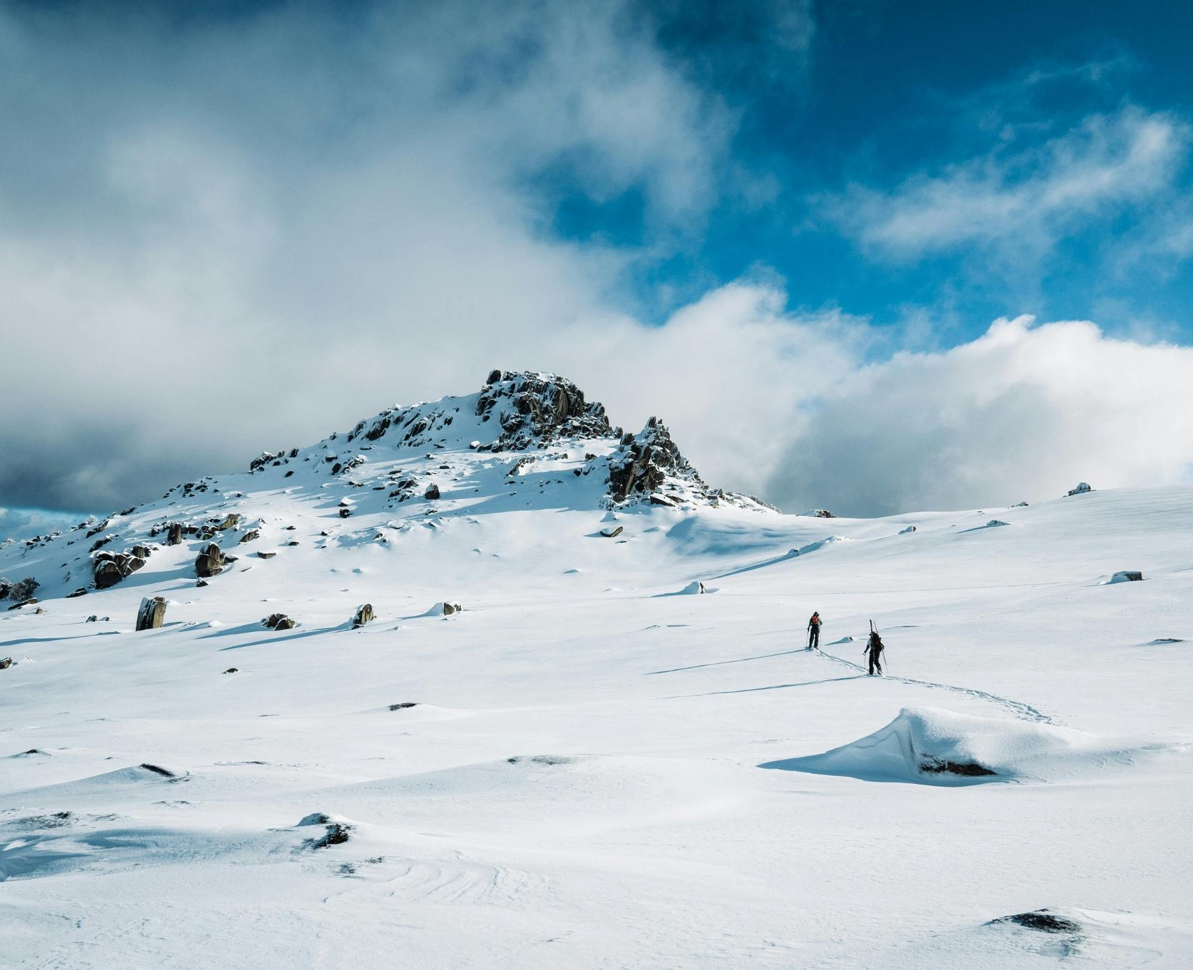 Two skiers walking up a mountain covered in snow