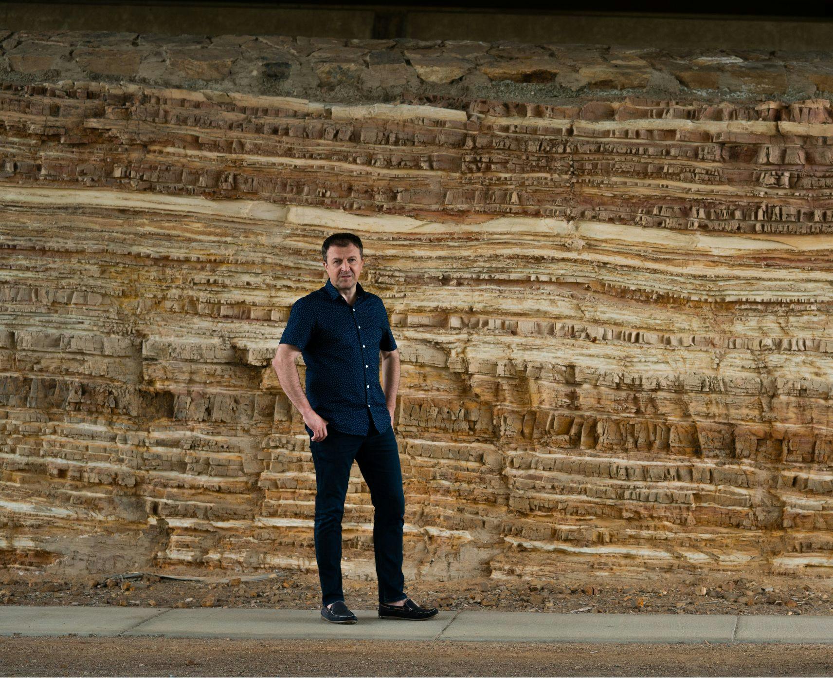 A man standing in front of rocky terrian.