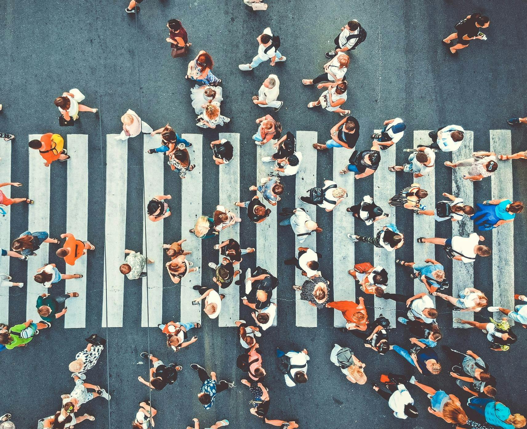 An aerial view of a crowd of people crossing a pedestrian crosswalk