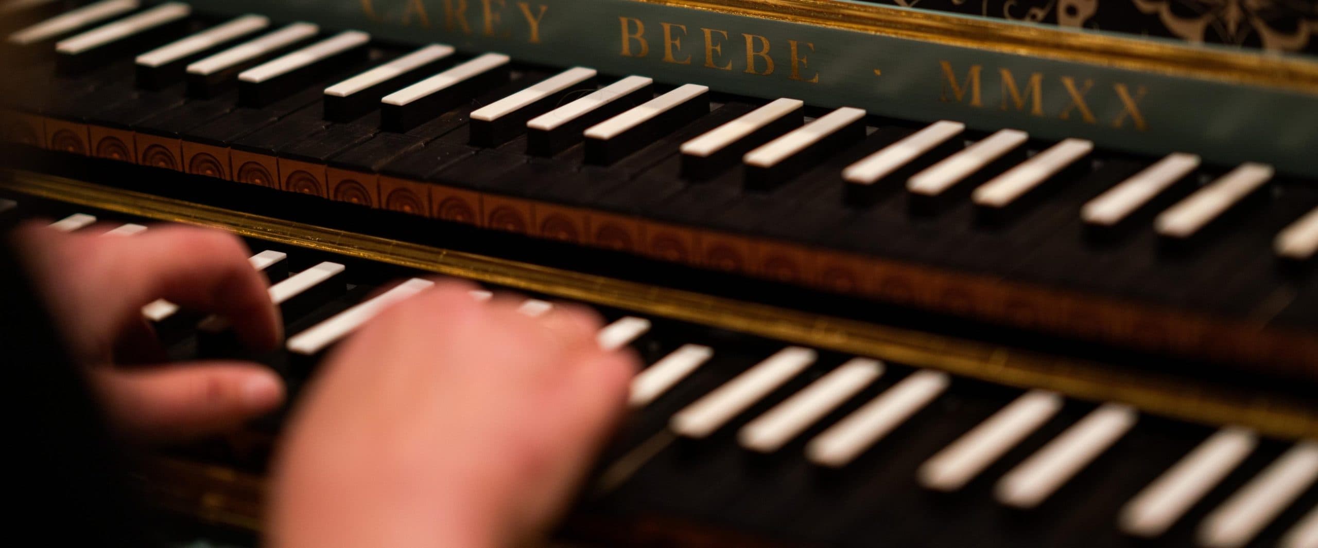A hand is shown pressing the keys on a keyboard. The keys are inverted: the natural notes are black, and the sharps and flats are white.