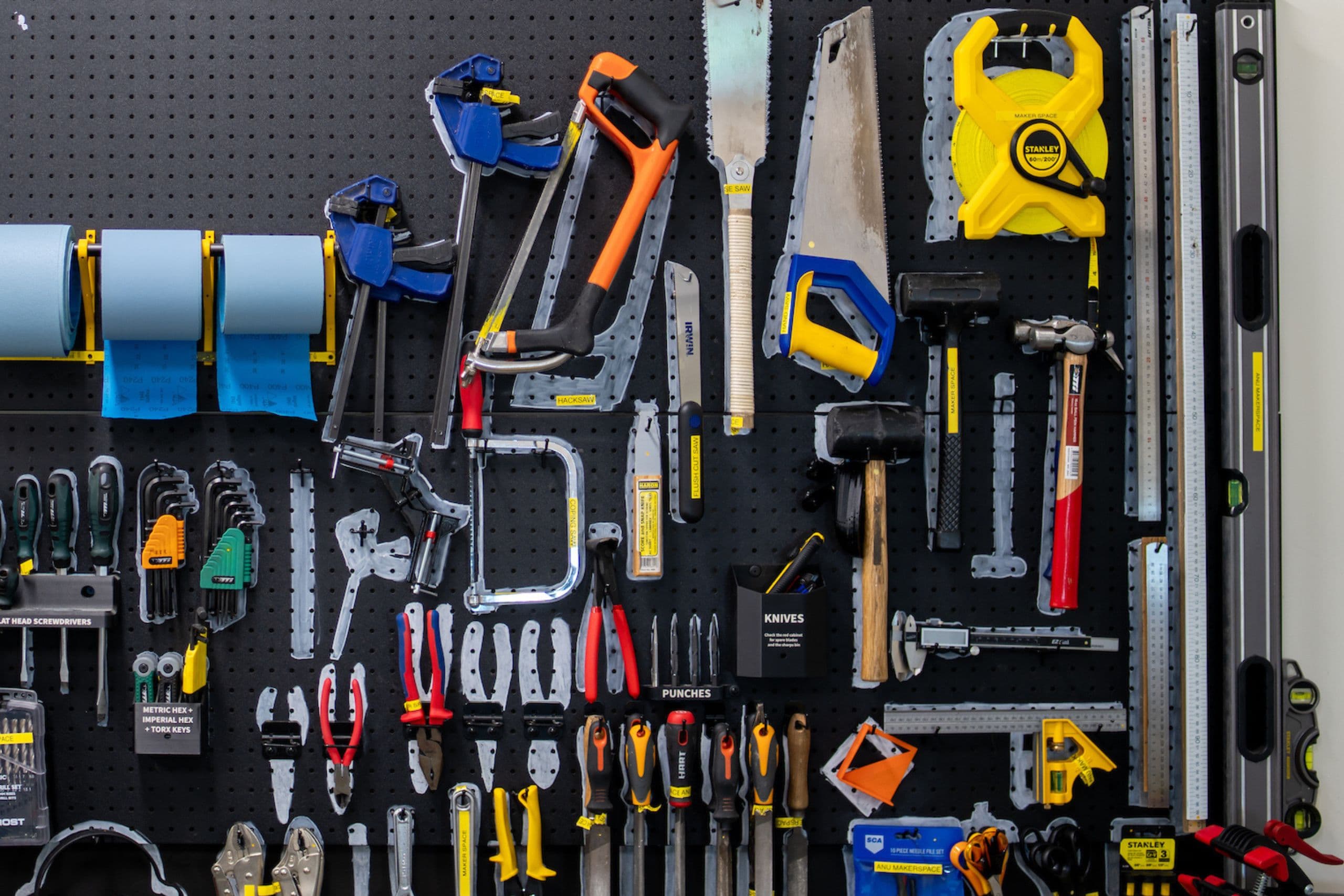 A wall with colourful tools hanging on a board