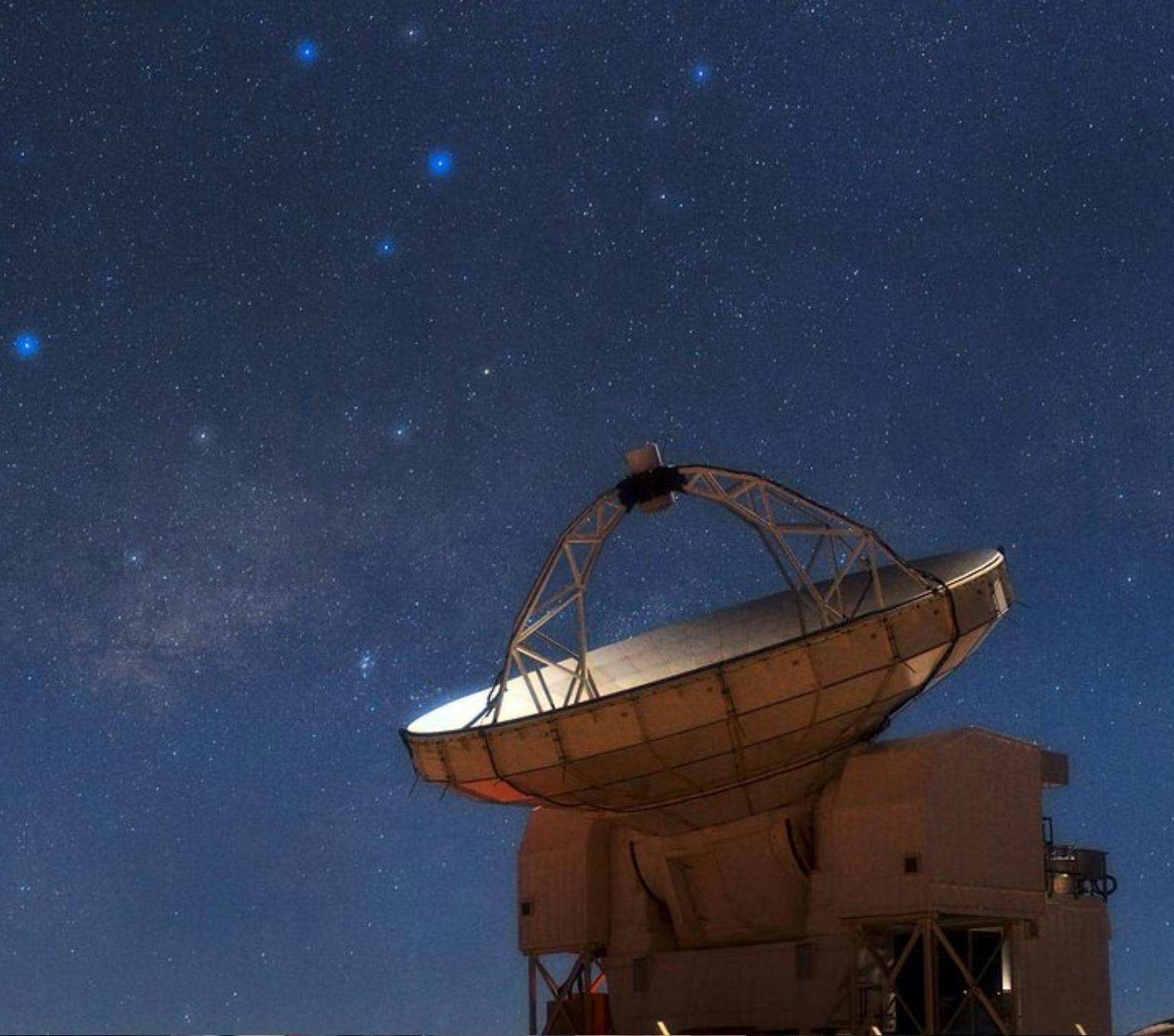 telescope with large metal dish is visible in front of a starry night sky