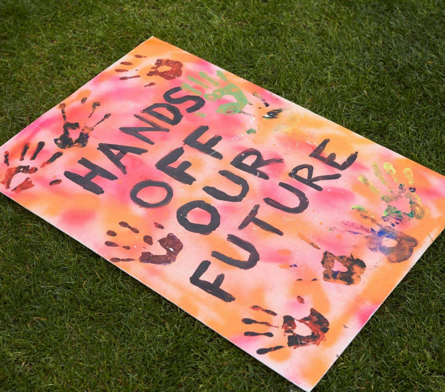 Handmade sign reading 'HANDS OFF OUR FUTURE".
