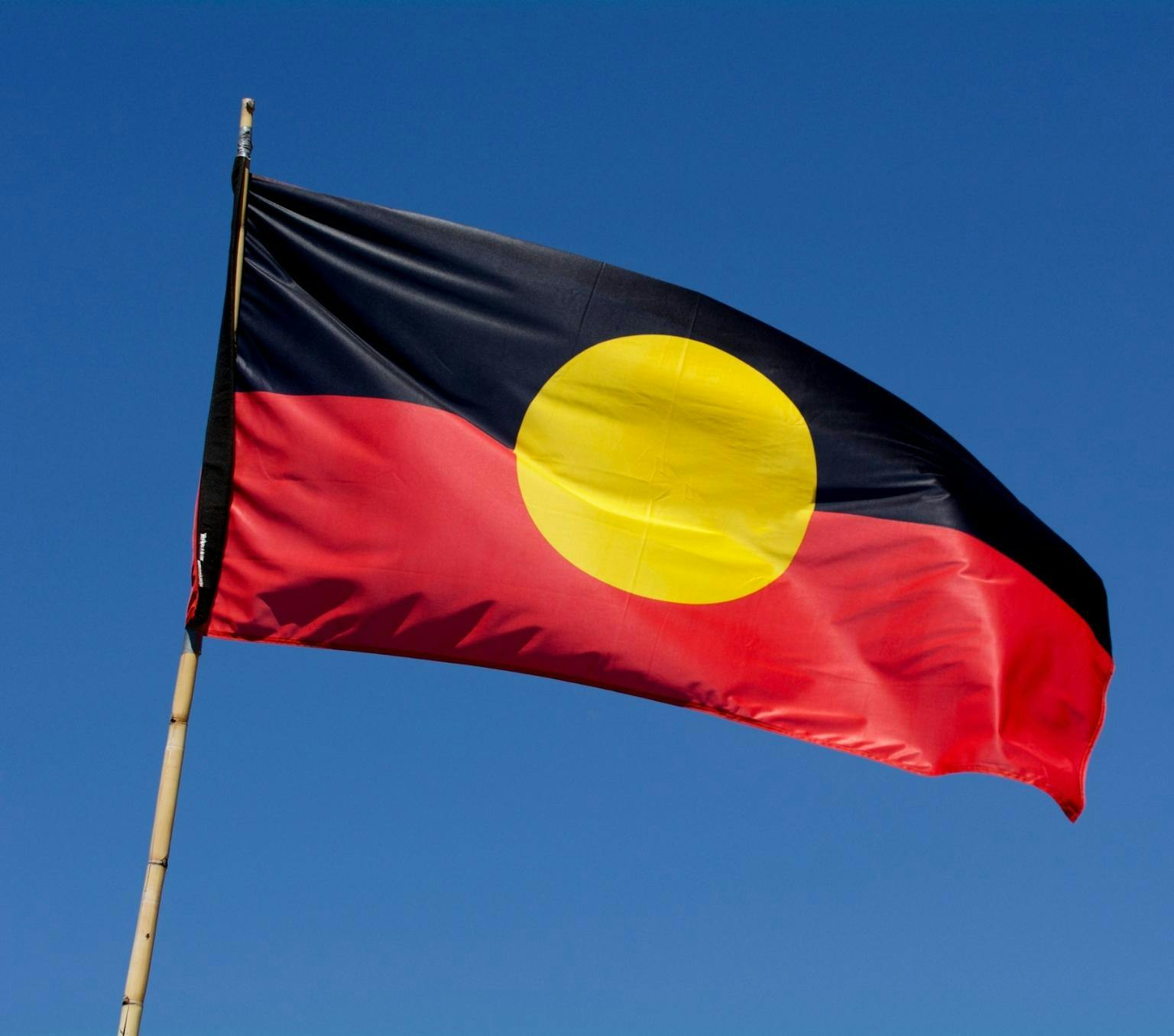 Aboriginal flag flying against a blue sky.