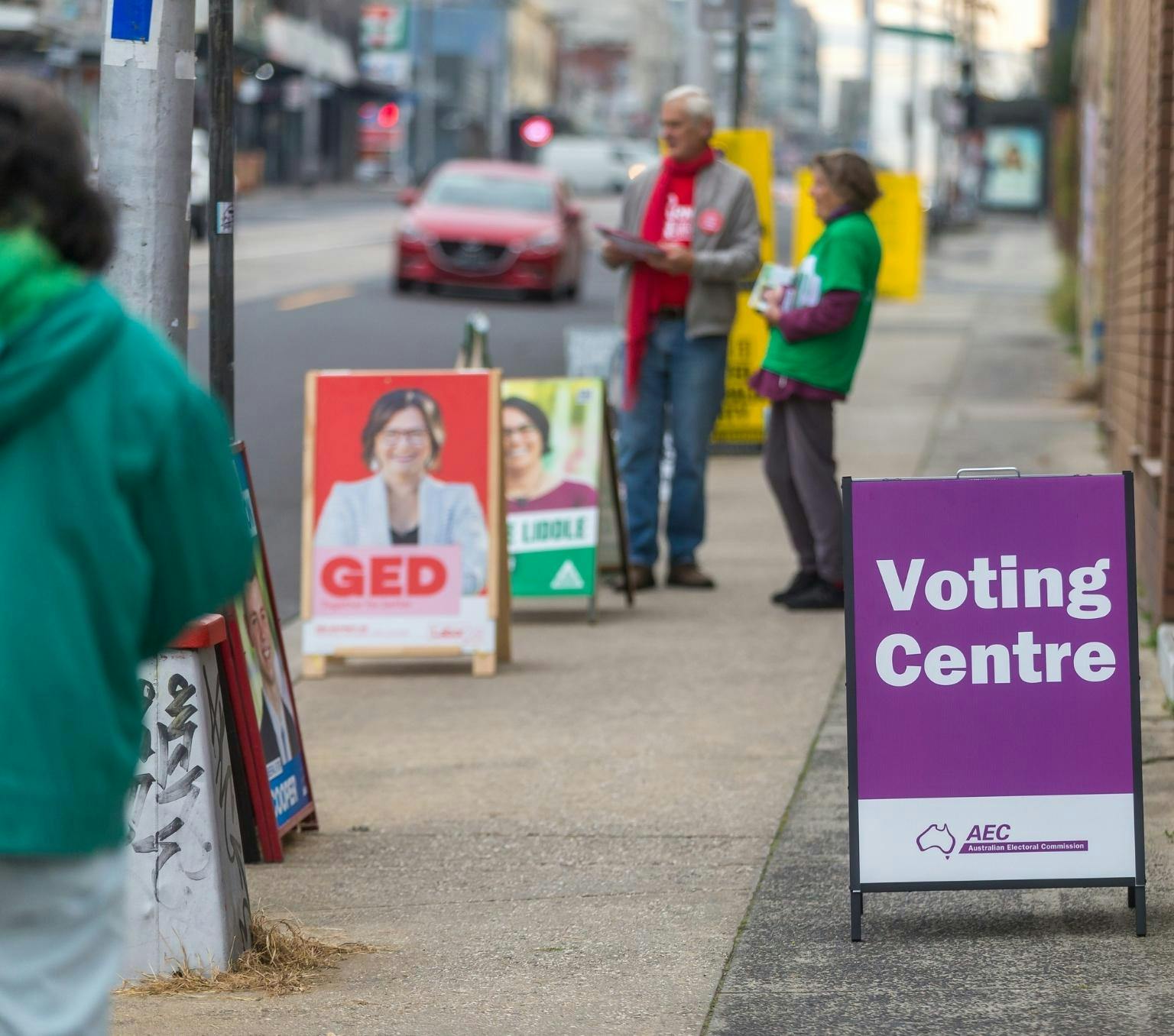 A-frame election posters on the footpath outside a polling booth. A purple sign says 'voting centre'.