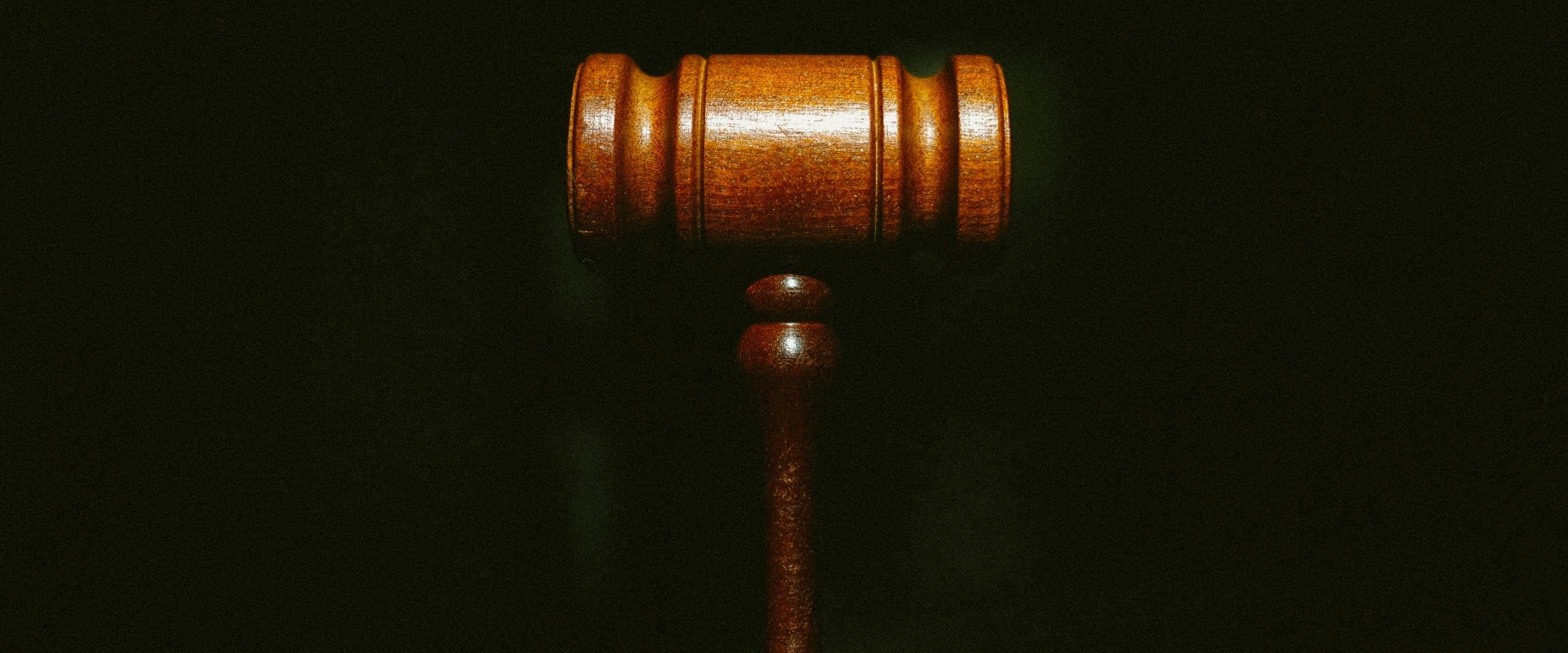A wooden gavel against a black background.