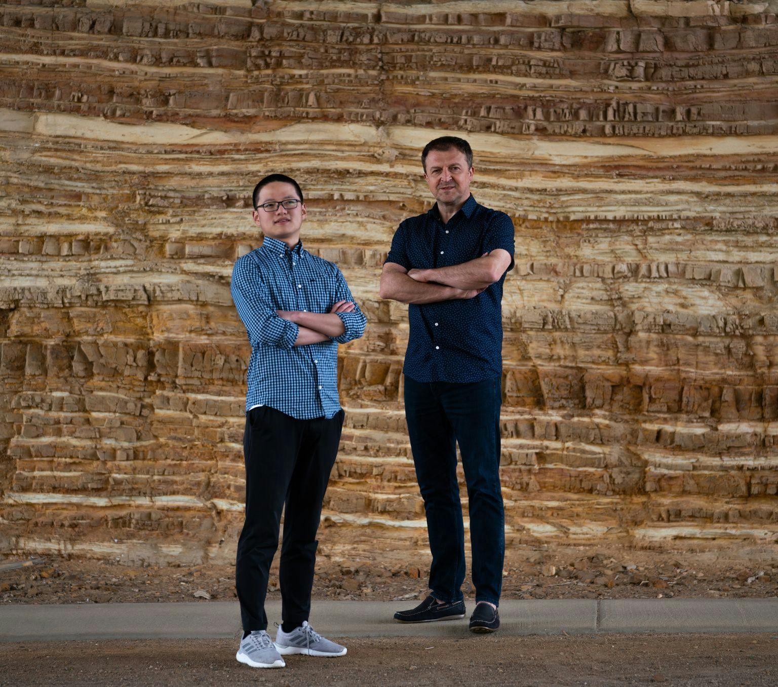 Sheng Wang and Professor Hrvoje Tkalčić stand in front of a multi-layered rock.