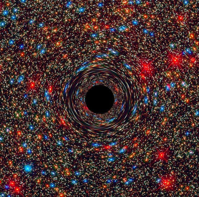 Computer-simulated image of a supermassive black hole. It is a swirl of thousands of red, blue and gold stars.