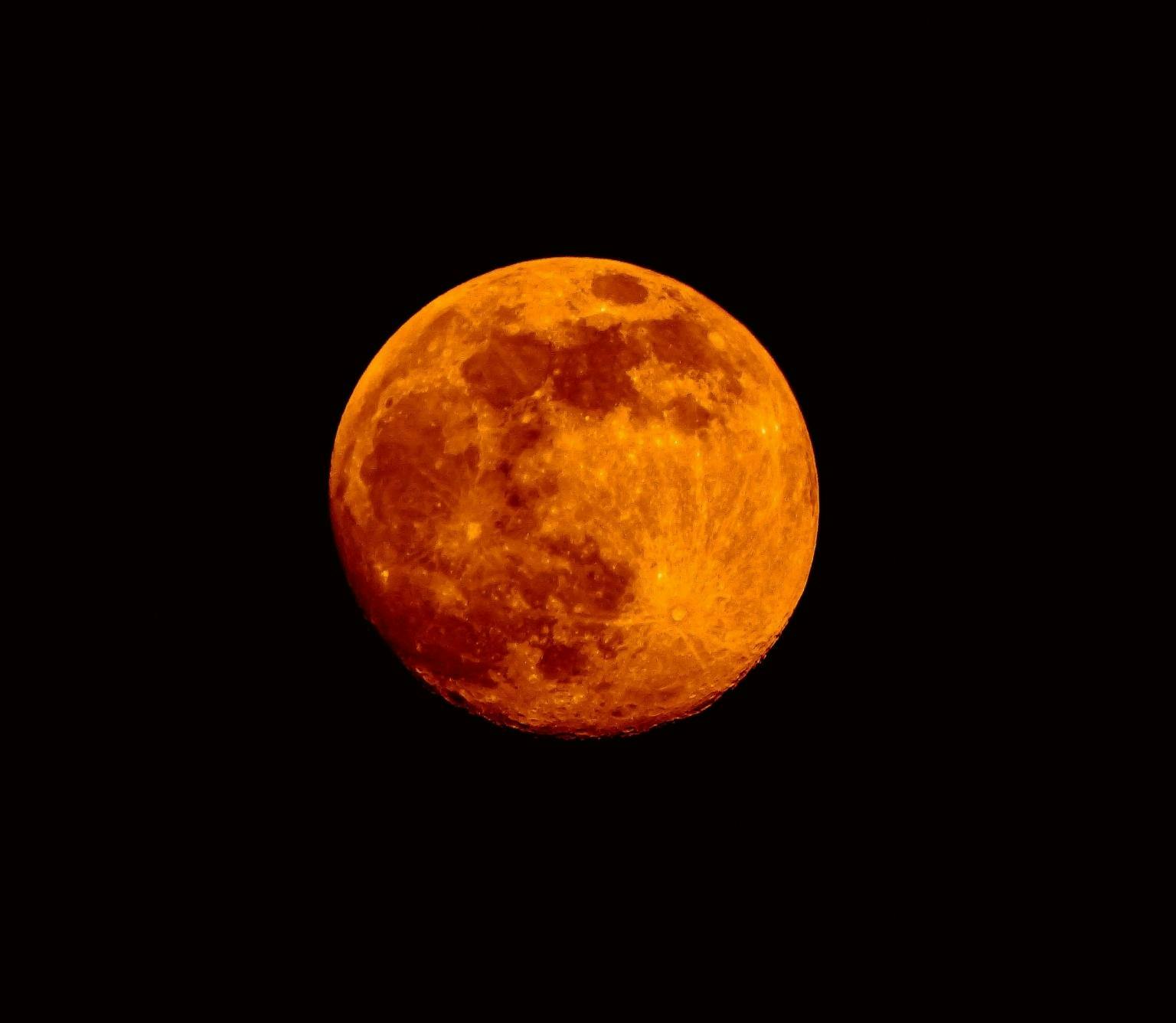 red blood moon is pictured in front of a black background