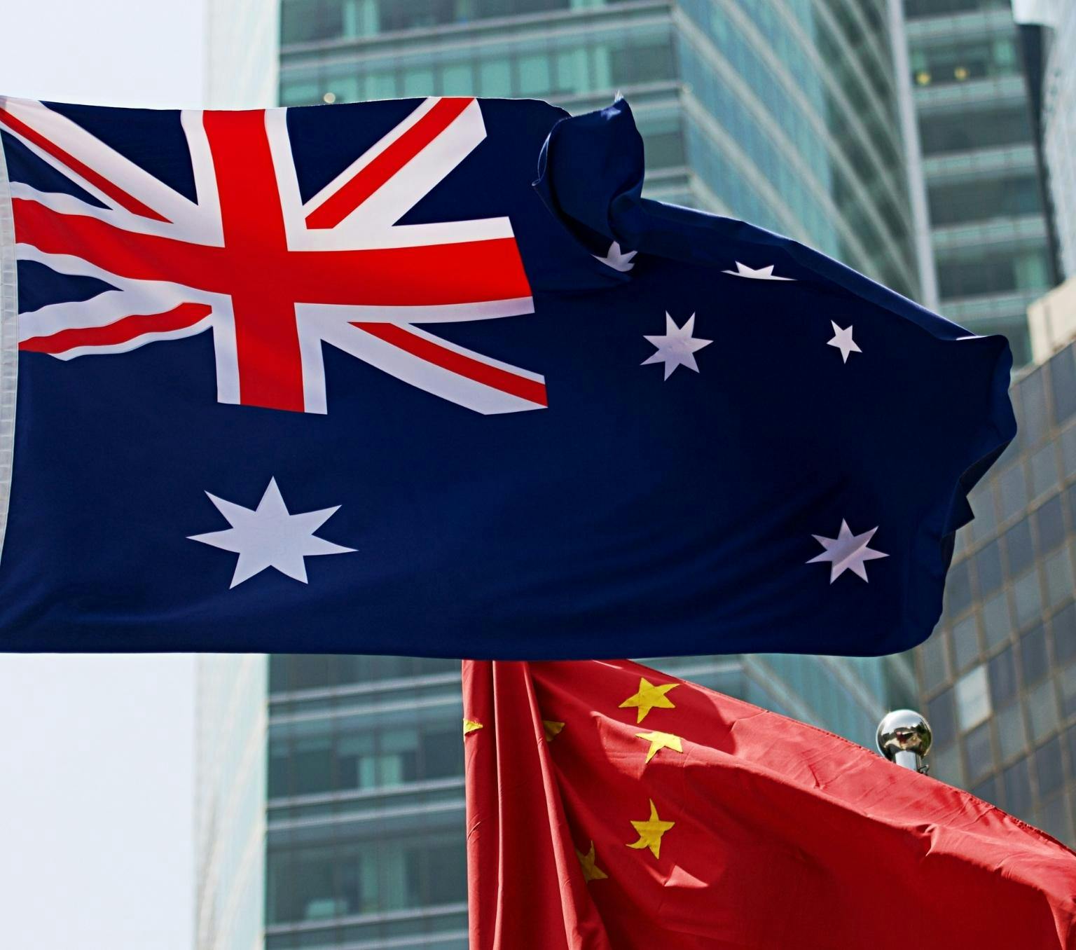 The Australian and Chinese flags fly in front of a tall building.