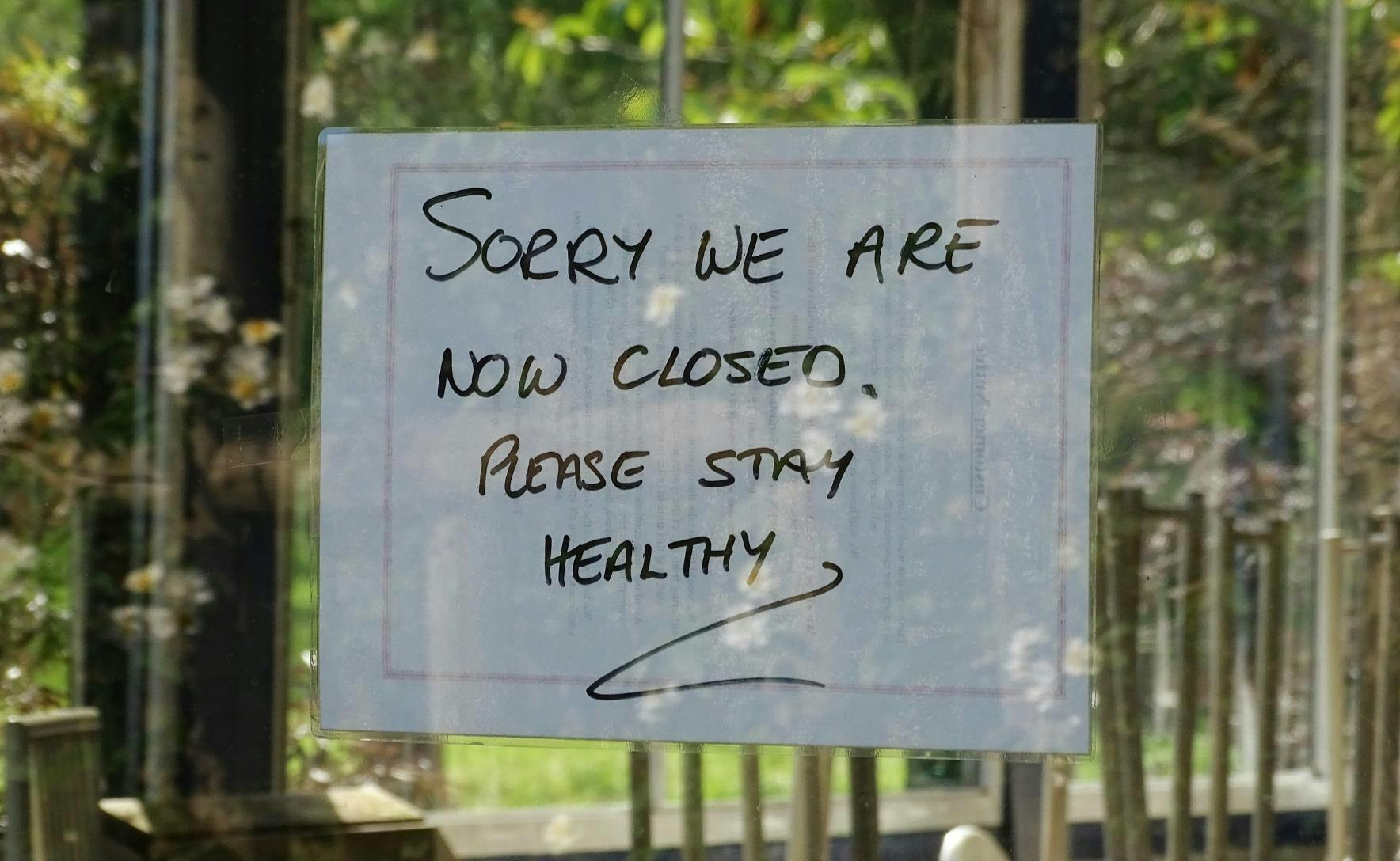 Sign on a glass door reads: sorry we are closed, please stay healthy.