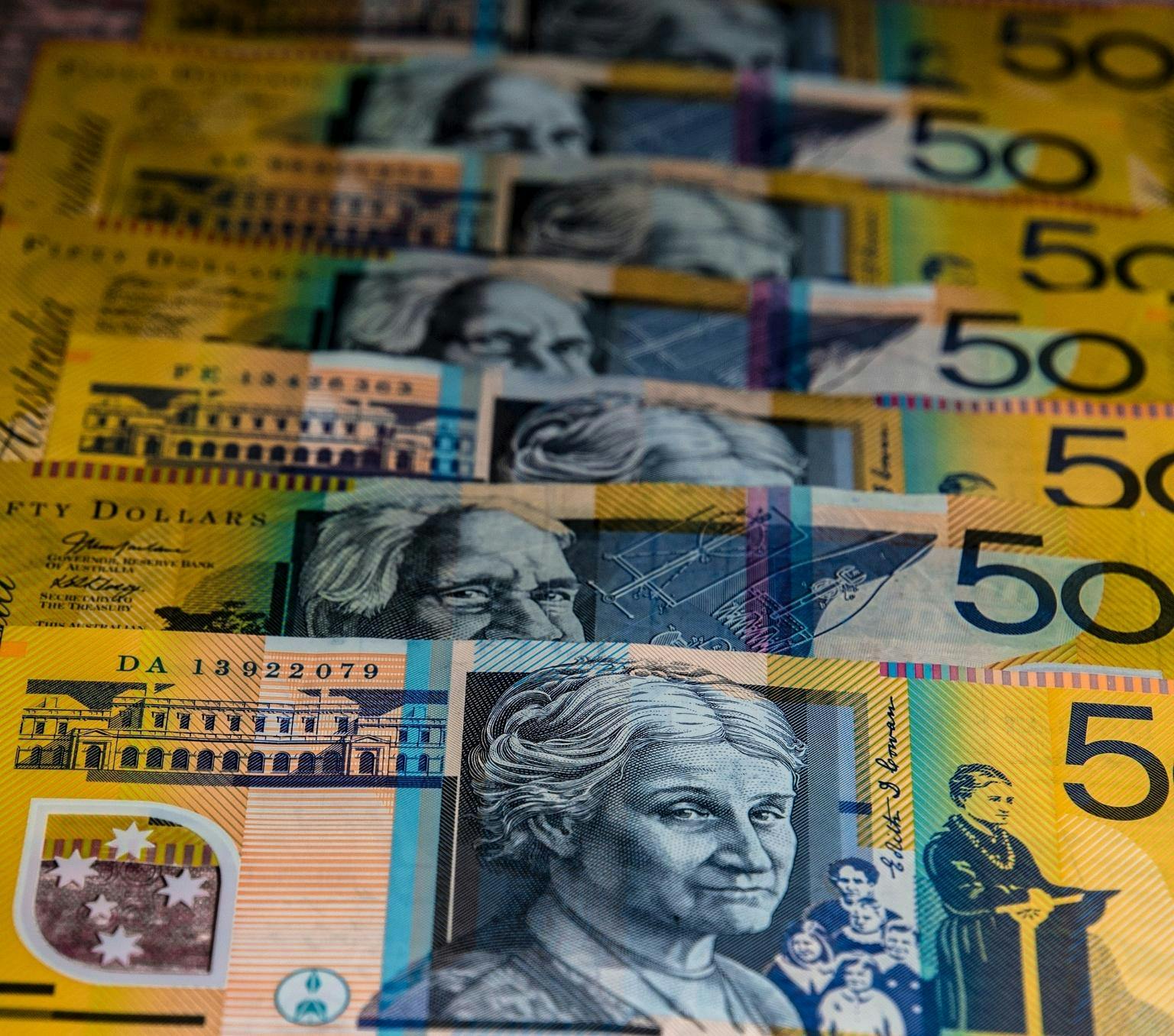 line of fifty dollar Australian bank notes. The notes are yellow and have a black and white image of a woman.