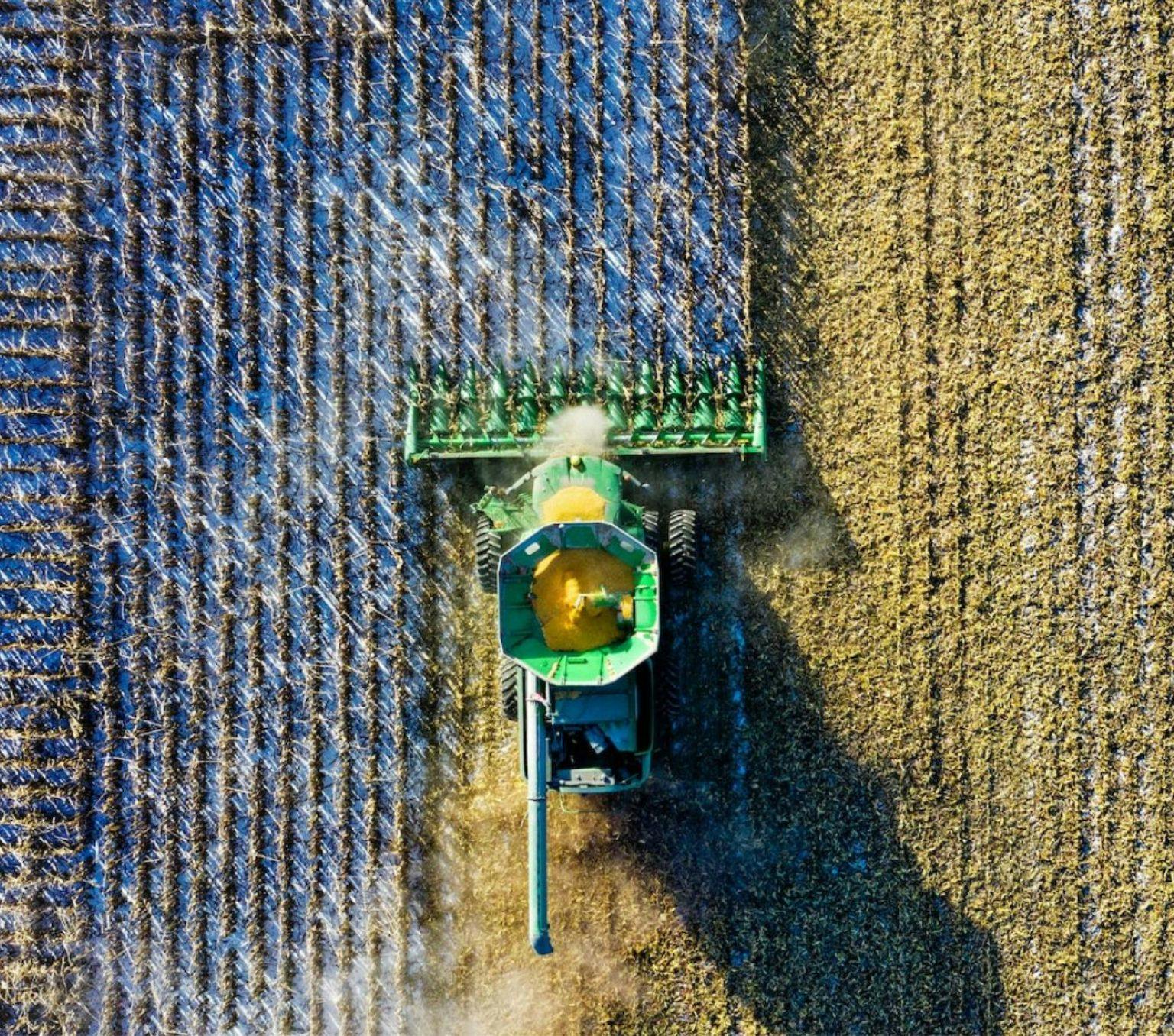 Aerial view of a green tractor milling through a paddock.