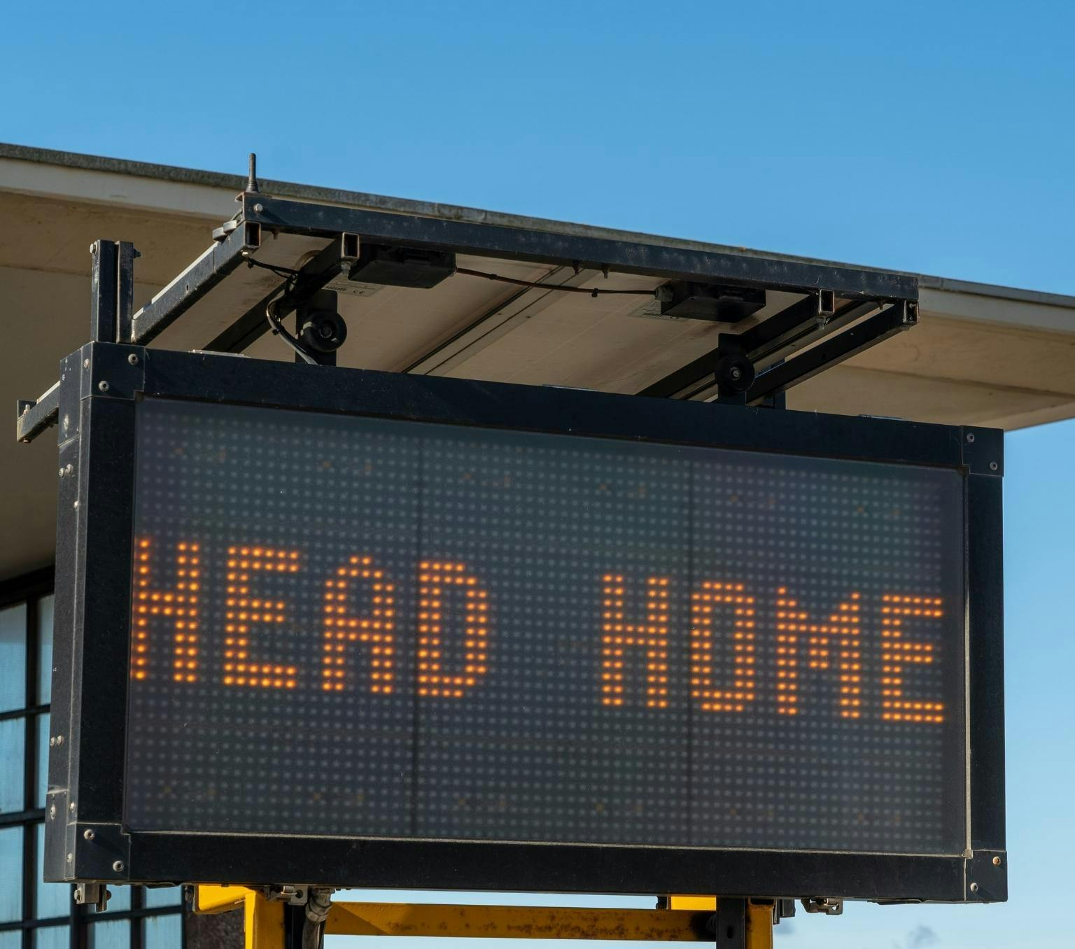 Black sign with yellow LED lights reading HEAD HOME. the background is a blue sky