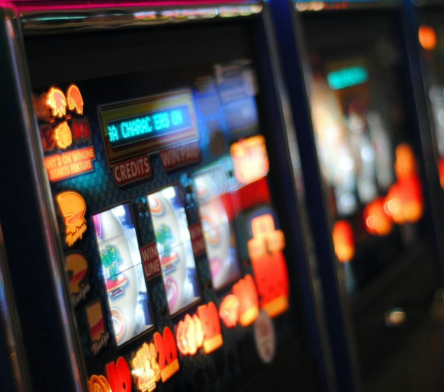 close up of pokie machines lined up in a row. There are yellow flashing lights on the machine