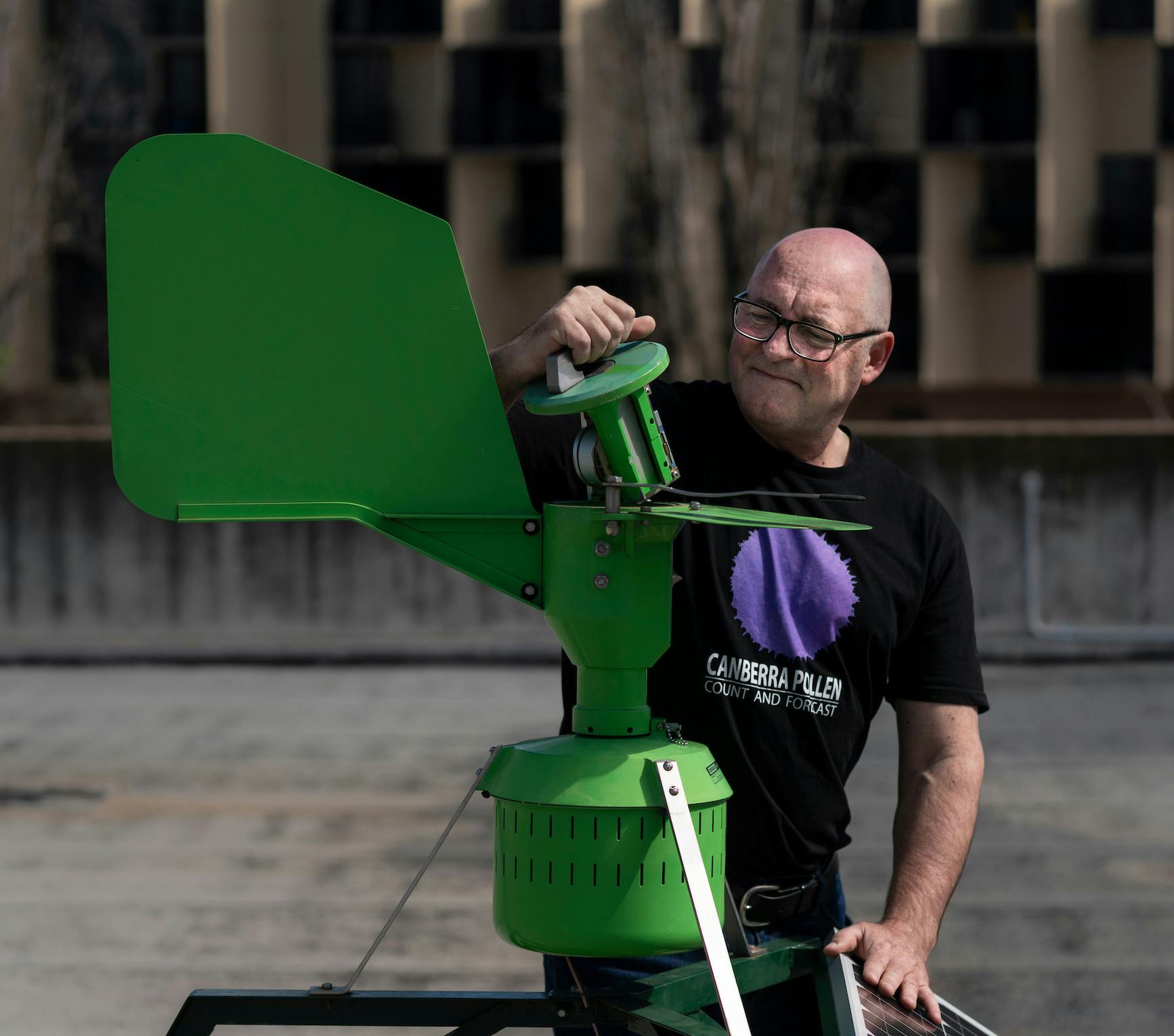 Simon Haberle pulls the top of a green metal machine, which is used to measure pollen.