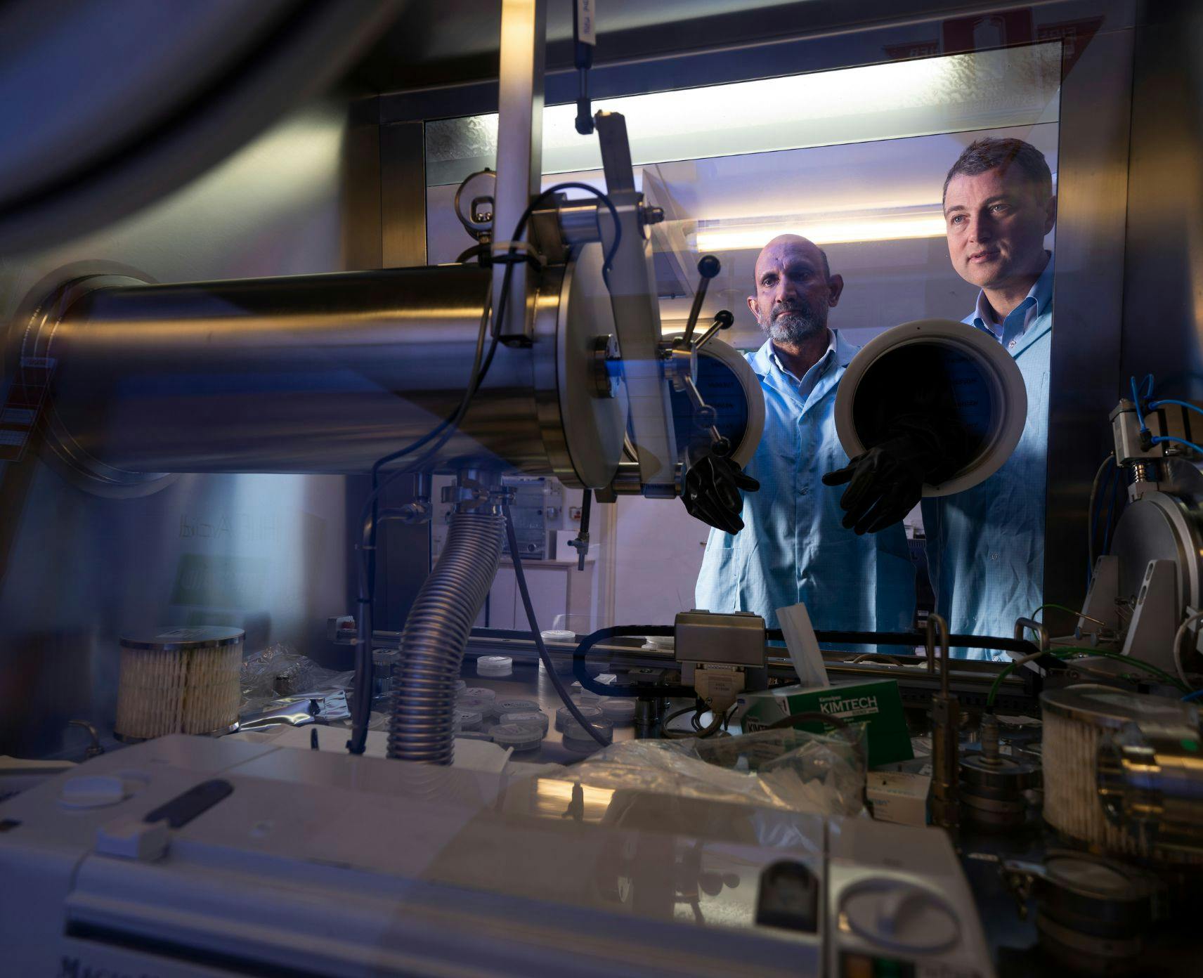 Two men looking through a piece of science machinery
