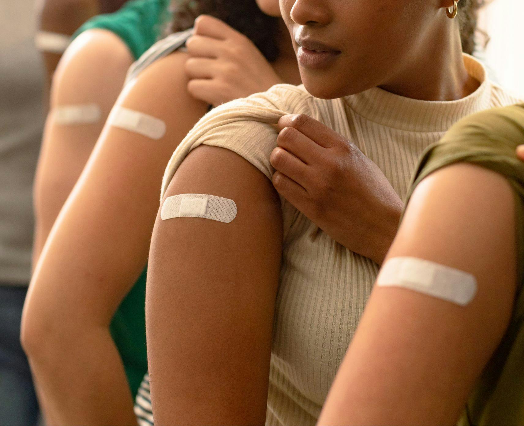 4 arms with band-aids on after vaccination