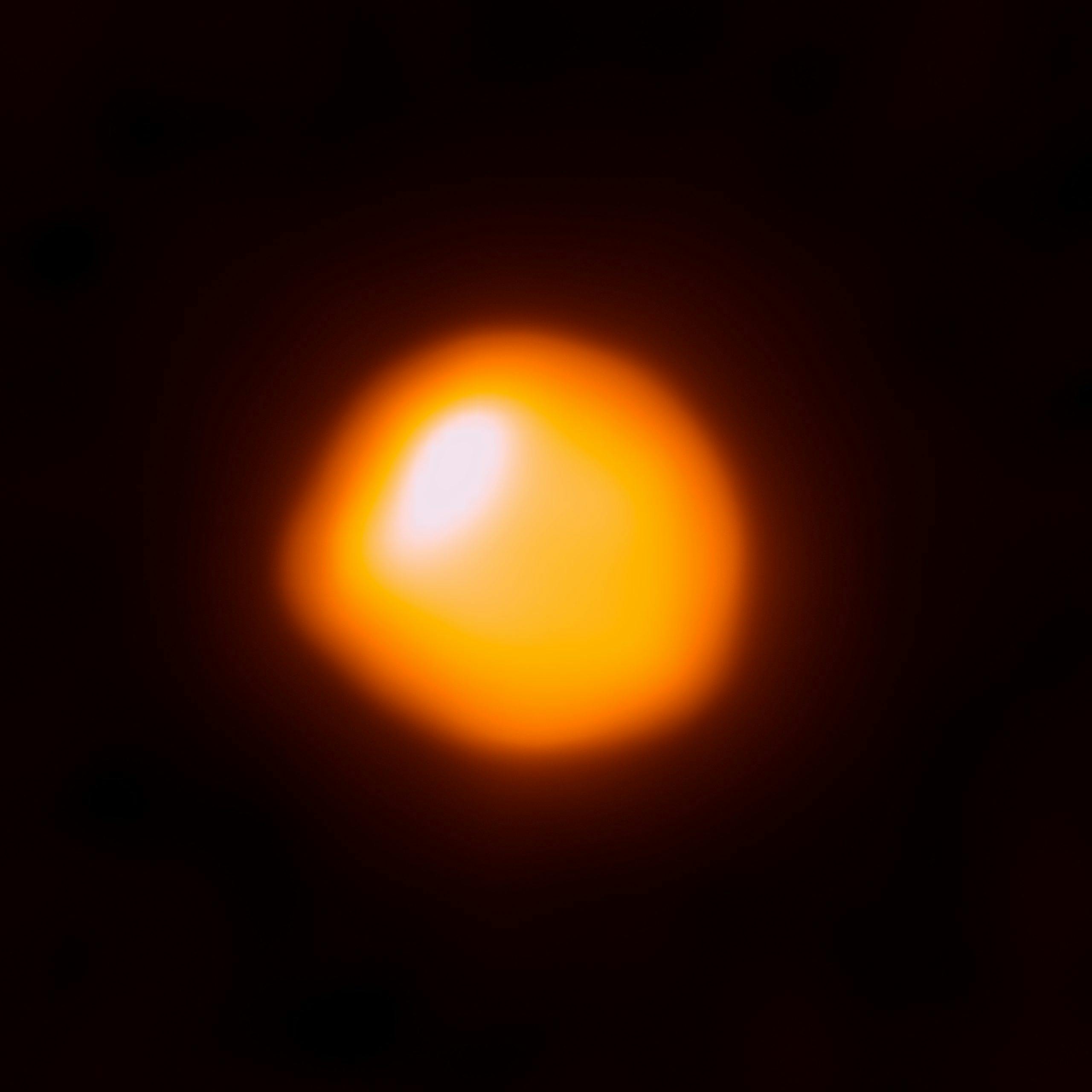red and orange ball of light glowing in front of a black background