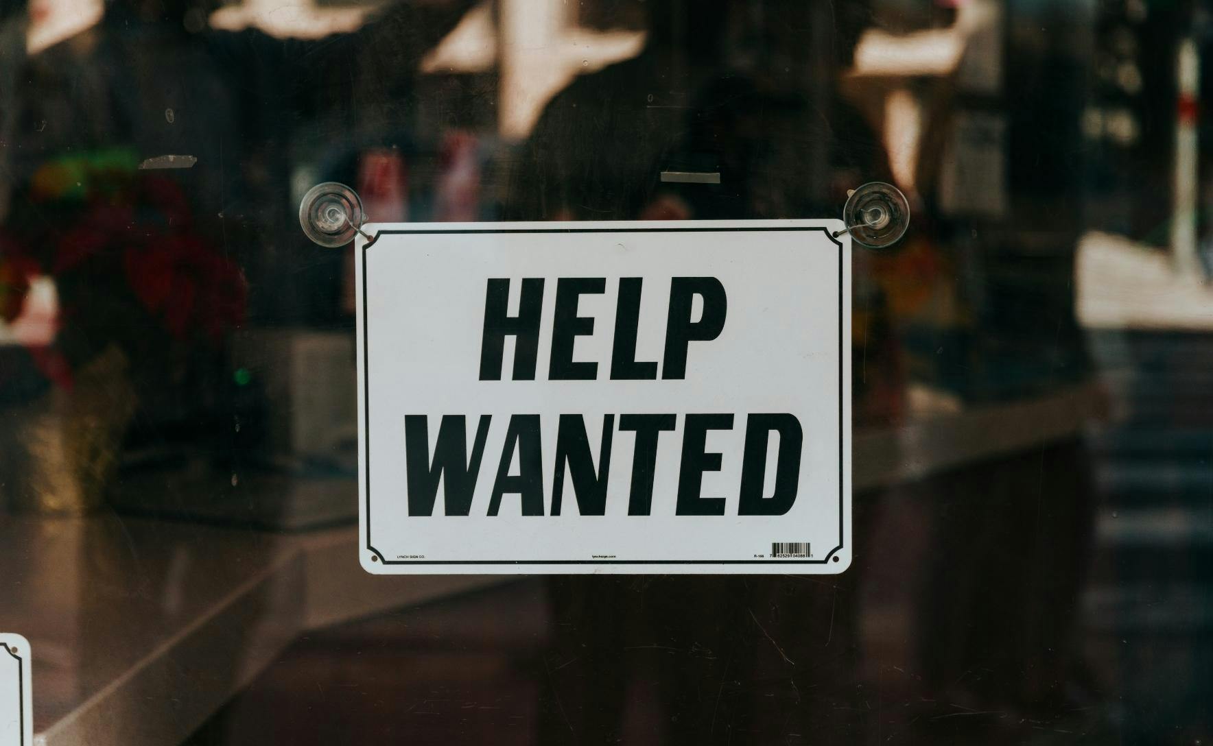 sign on a glass door reading help wanted