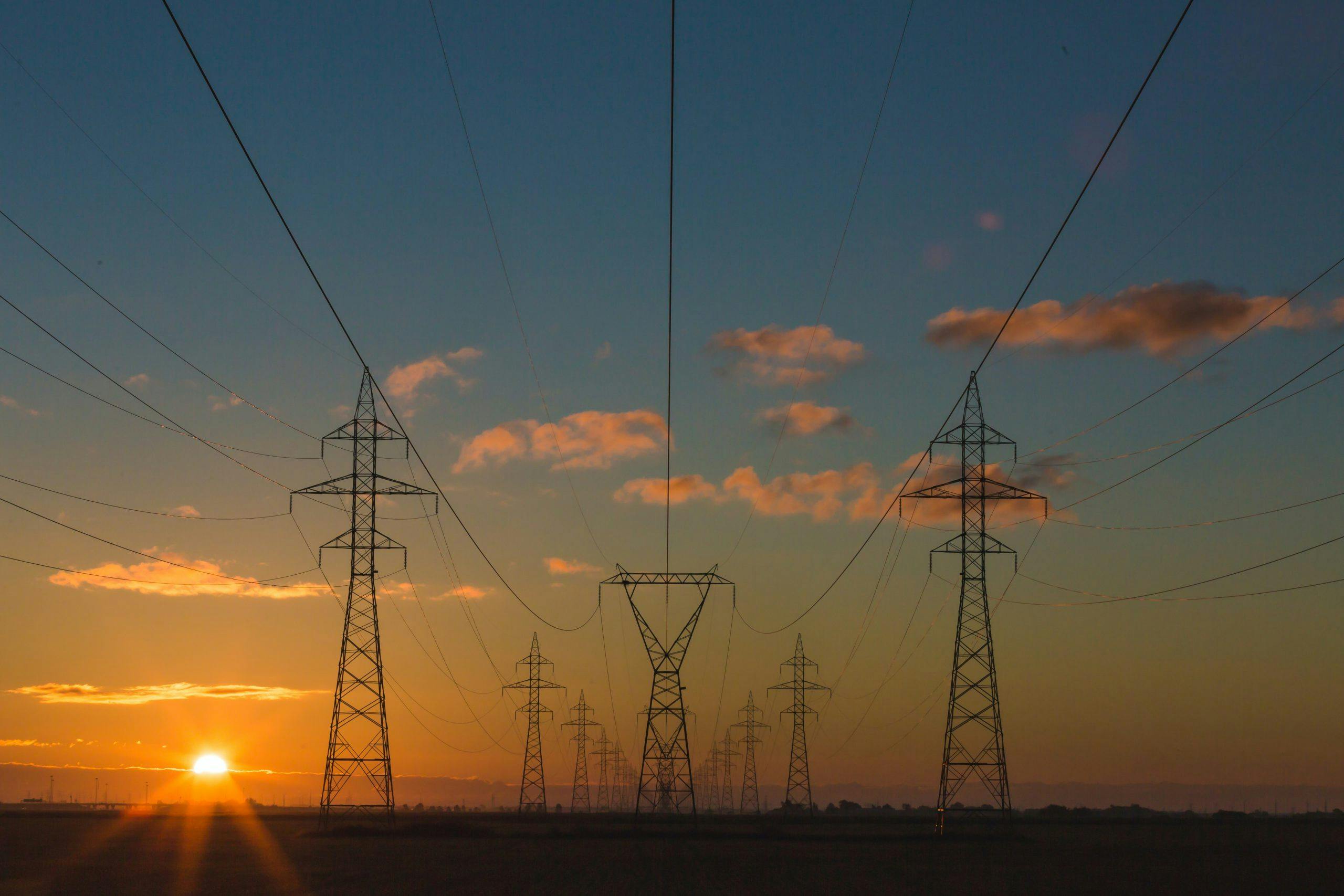 sunset image of power lines reaching into the distance along a flat landscape