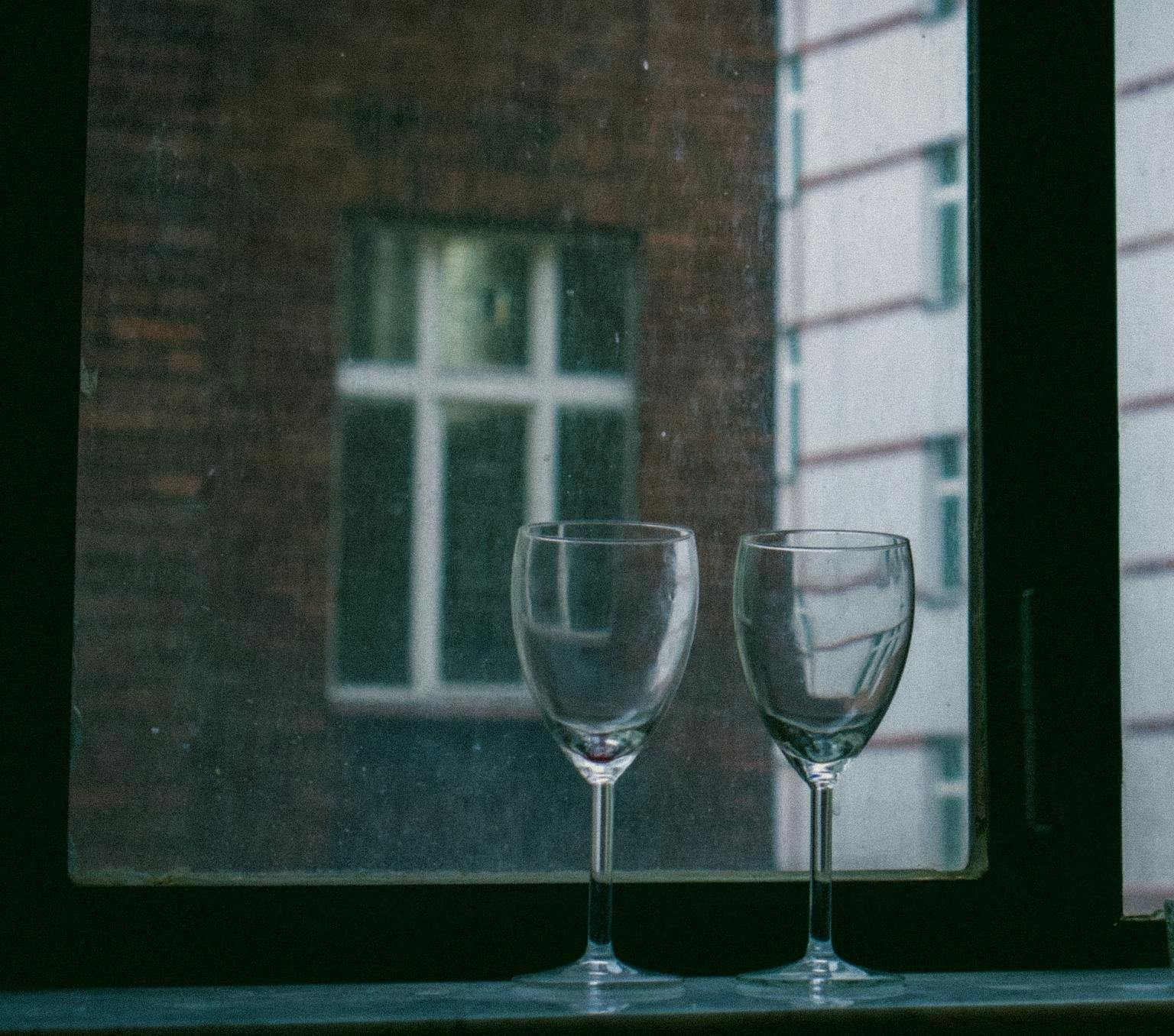 two empty wine glasses in front of a window