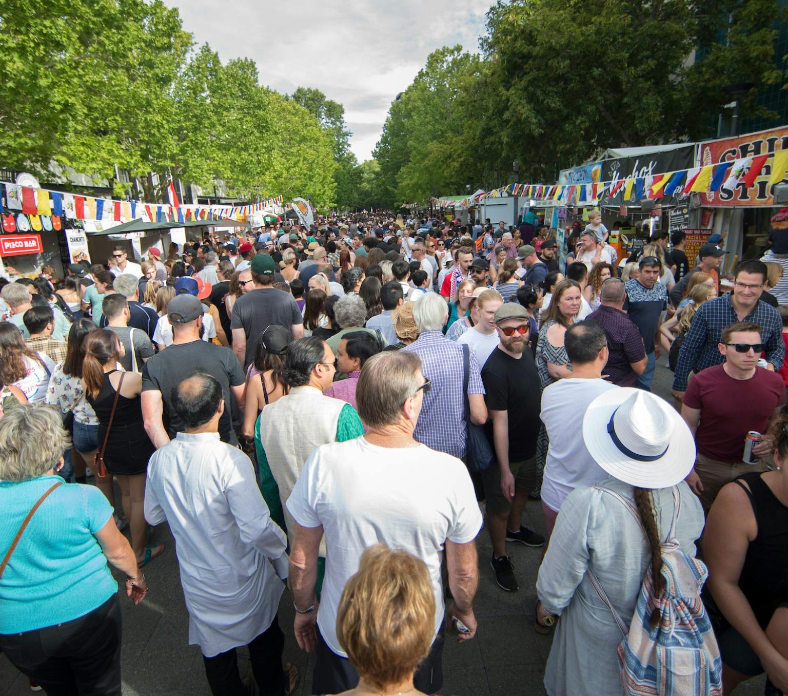 crowd of people in a street lined with food stalls