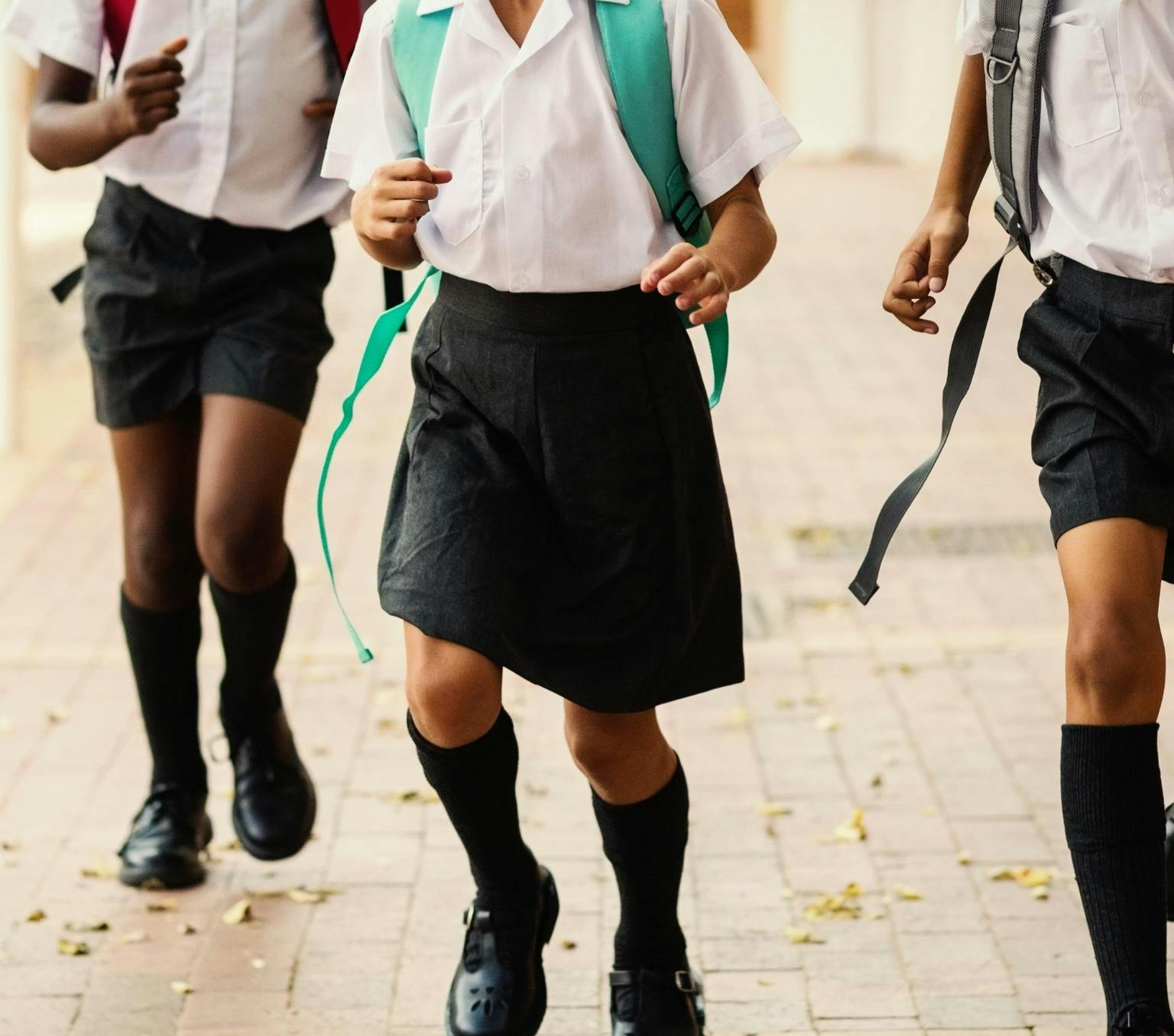 three kids pictured from the chest down running in school uniform
